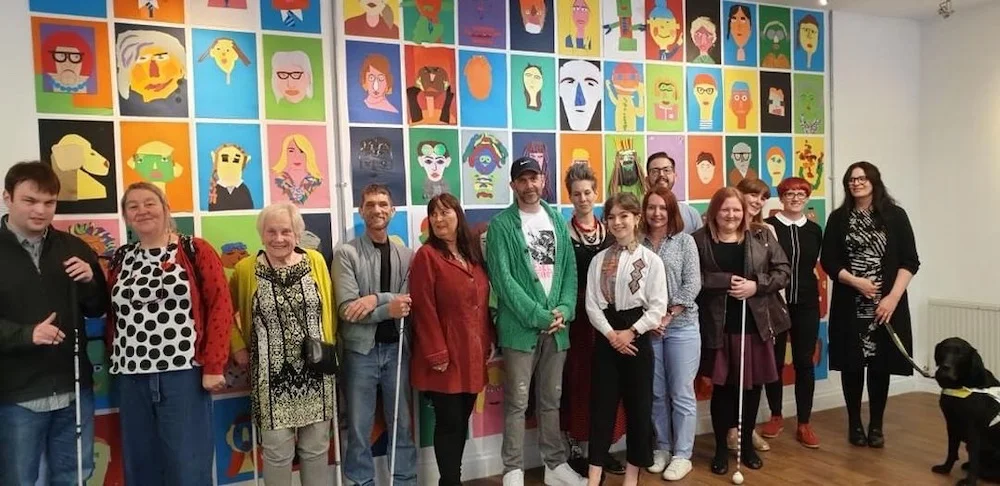 Some of the project’s participants and facilitators in front of the portrait wall