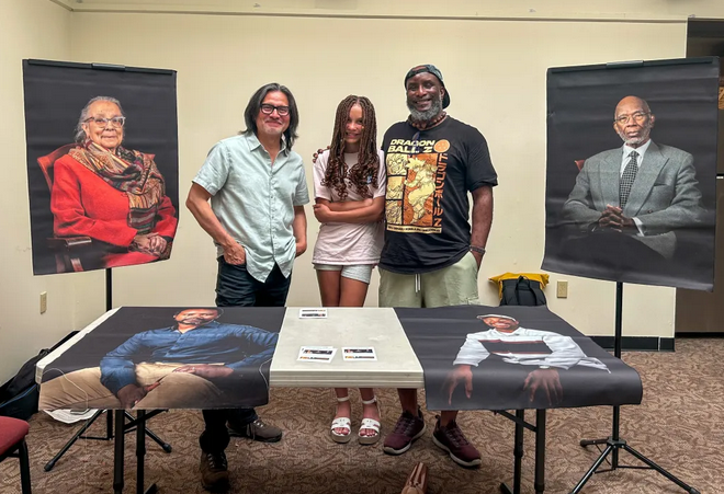 René Rentería, Amina Rhoads and Rajnii Eddins standing at a table in support of the Vibrant Lives Project. Photo by Emily Rodin.