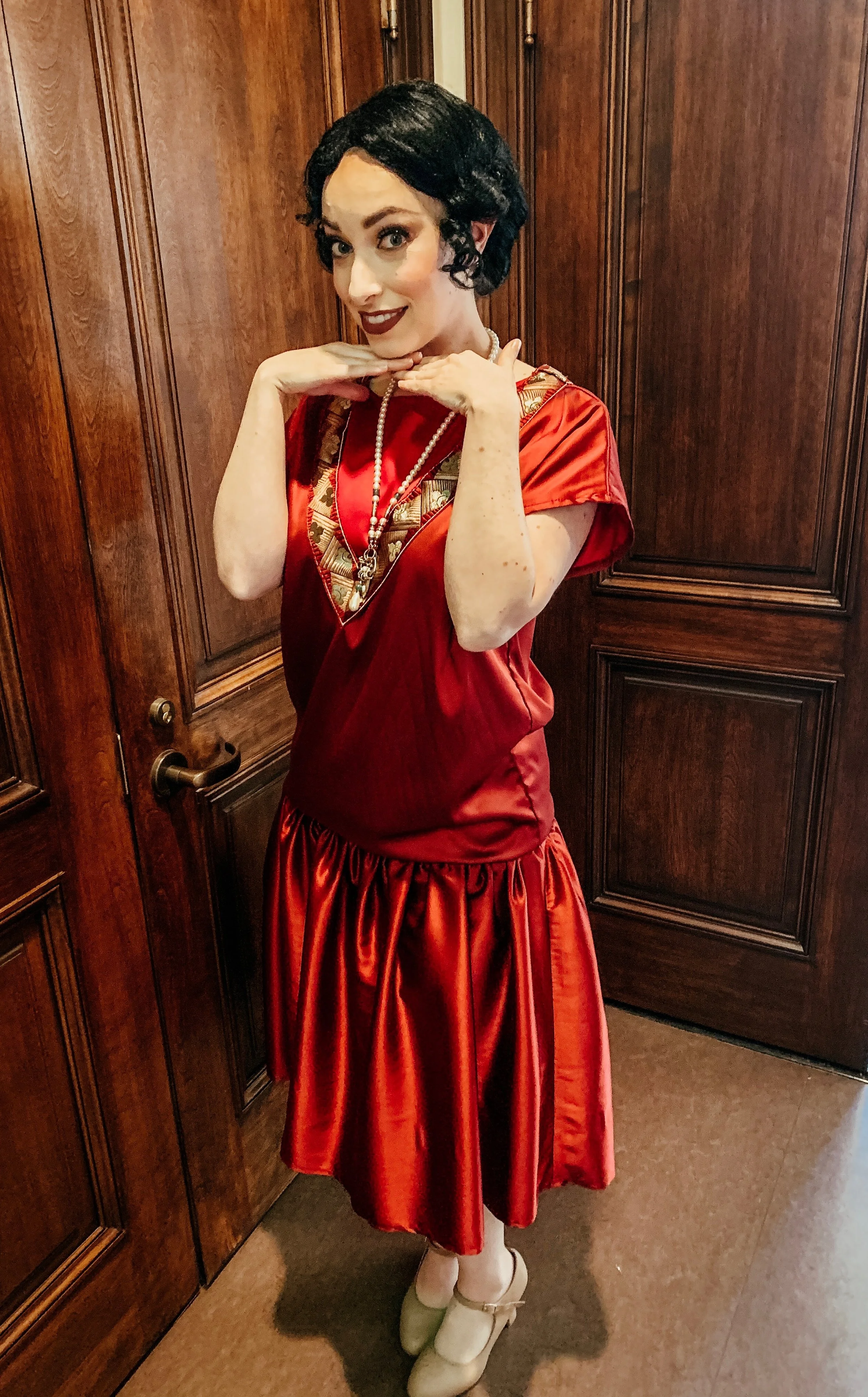  Leslie wearing red dress and black wig, backstage of  Downton AirBnB: The Nurse’s Wish.  