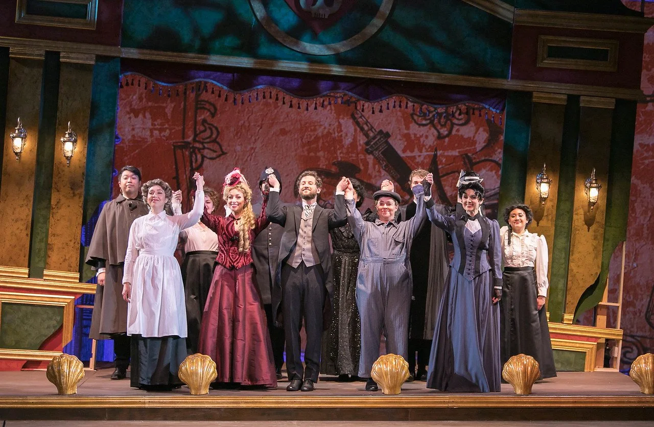  Leslie as Sibella Hallward ,  wearing burgundy dress and blond wig, in  A Gentleman’s Guide to Love and Murder  with Lamplighters Music Theatre, pictured with full cast. Photo by Joe Giammarco. 