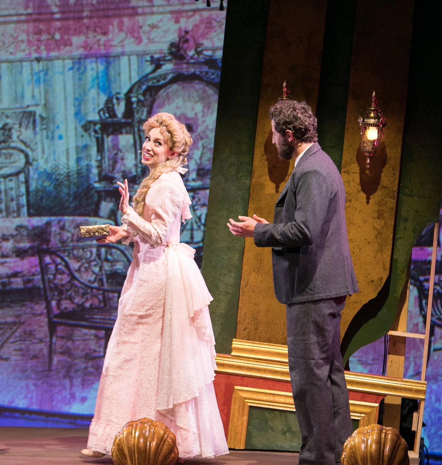 Leslie as Sibella Hallward, wearing pink dress and blond wig, in  A Gentleman’s Guide to Love and Murder  with Lamplighters Music Theatre, pictured with castmate. Photo by Lucas Buxman. 