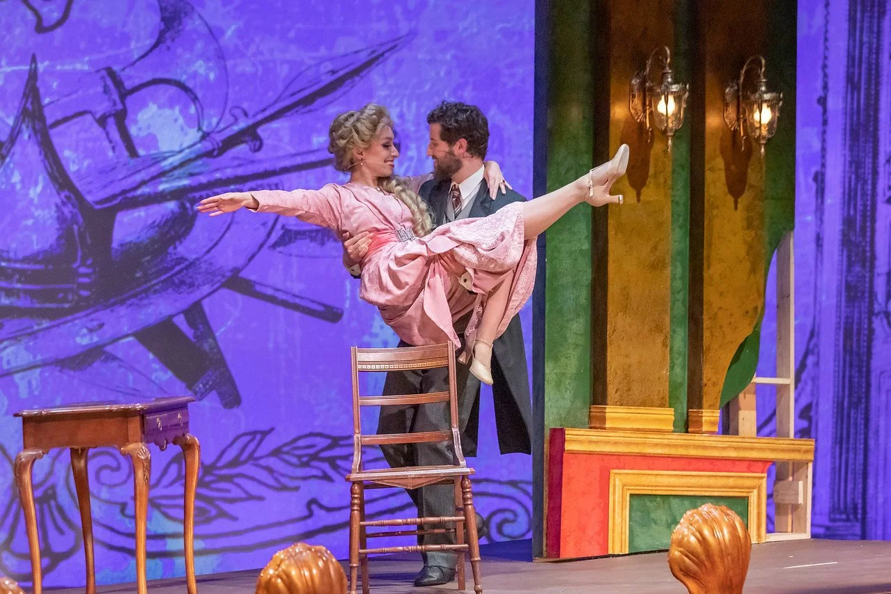 Leslie in pink dress and blond wig, with cast mate, in A Gentleman's Guide to Love and Murder.