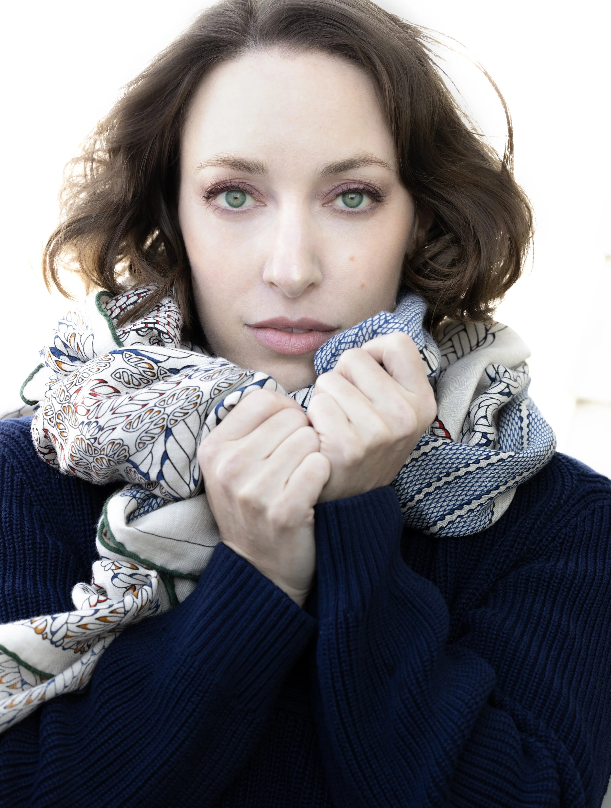 Leslie in blue sweater with white scarf wrapped around neck. Photo by Gian Andrea di Stefano.