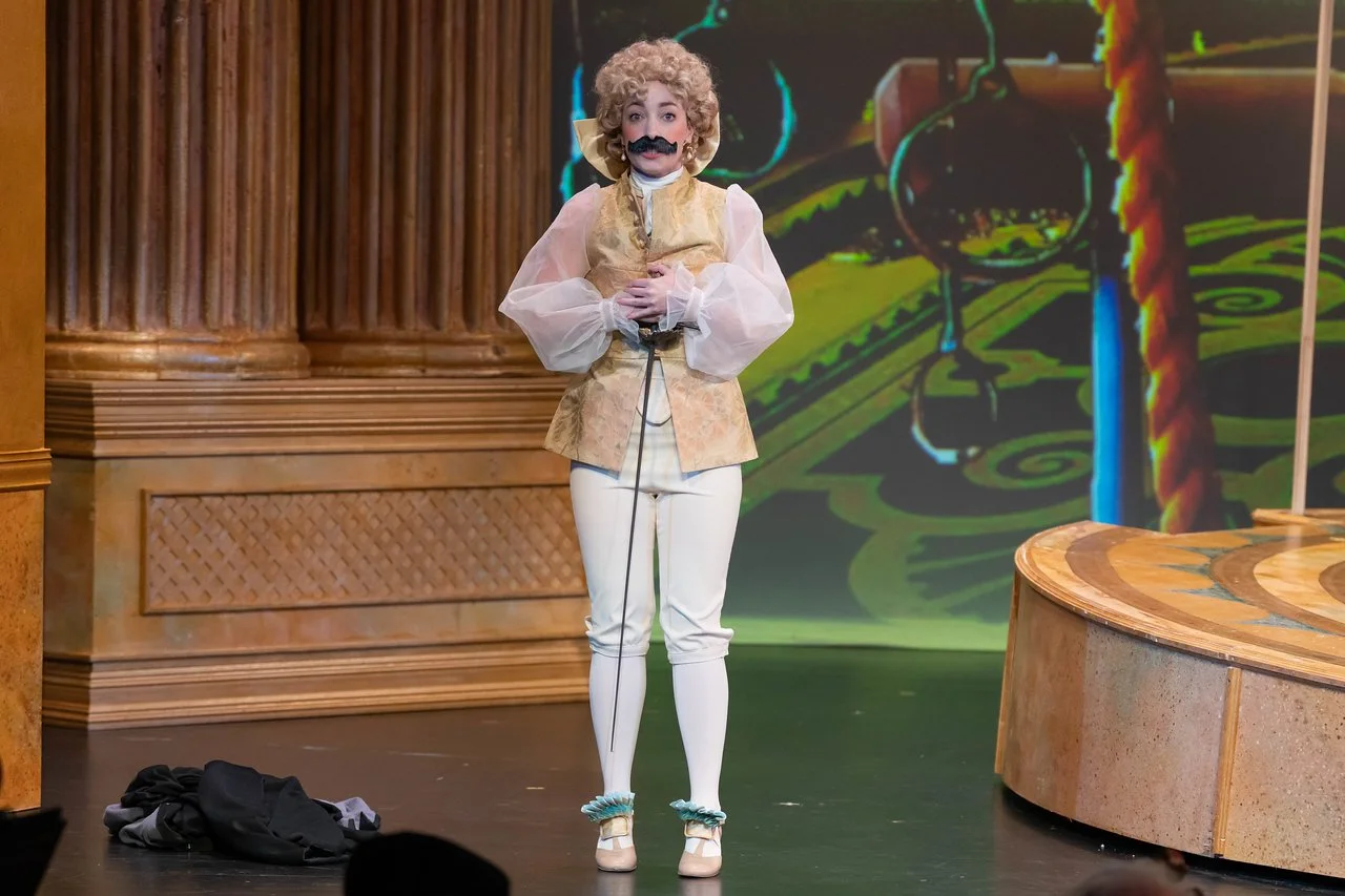  Leslie as Lady Lilette Sauvoirfaire, wearing white pants, gold vest, and blond wig, in  By Georges!  with Lamplighters Music Theatre. Photo by Joe Giammarco. 