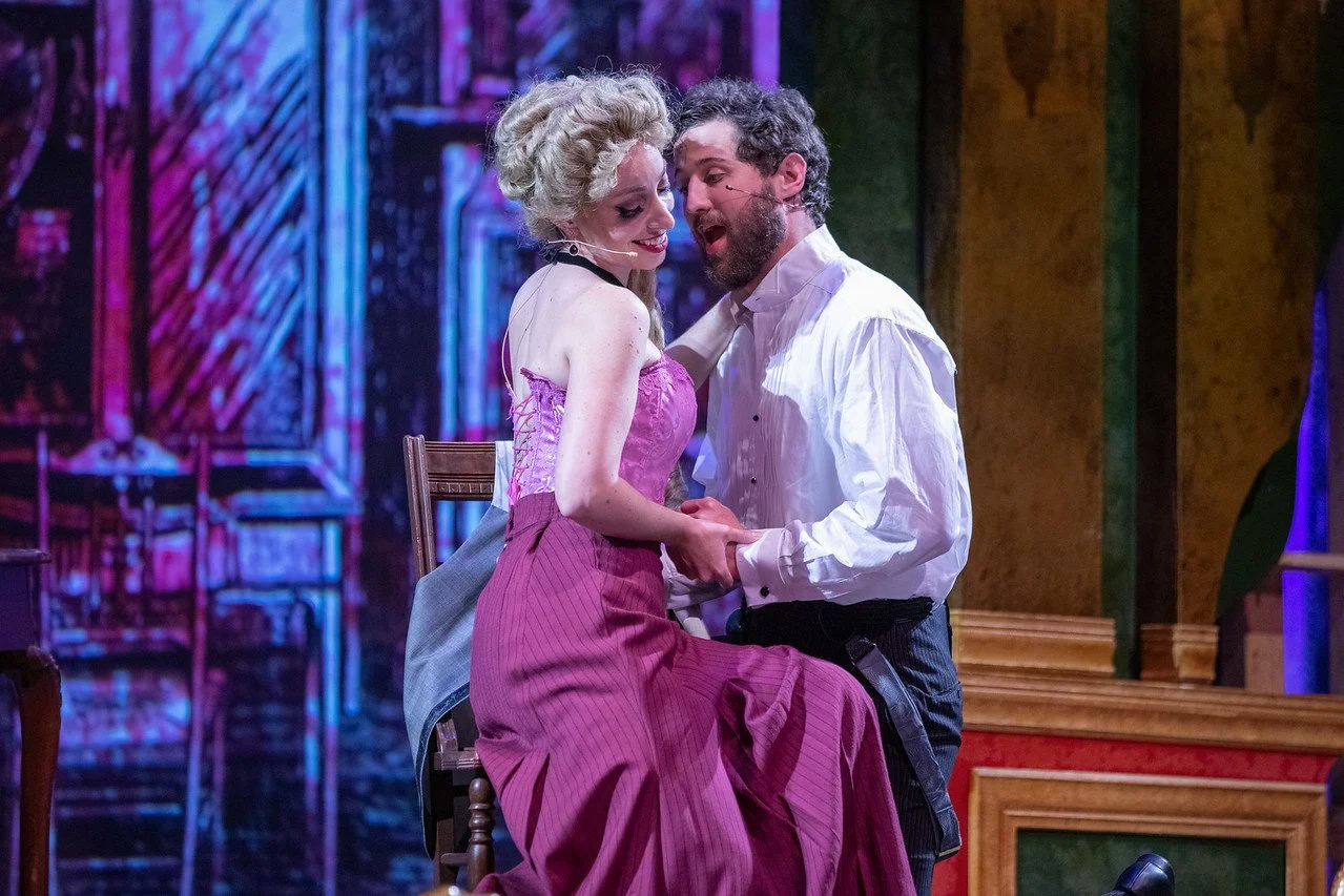  Leslie as Sibella Hallward ,  wearing pink dress and blond wig,   in  A Gentleman’s Guide to Love and Murder  with Lamplighters Music Theatre, pictured with castmate. Photo by Joe Giammarco. 