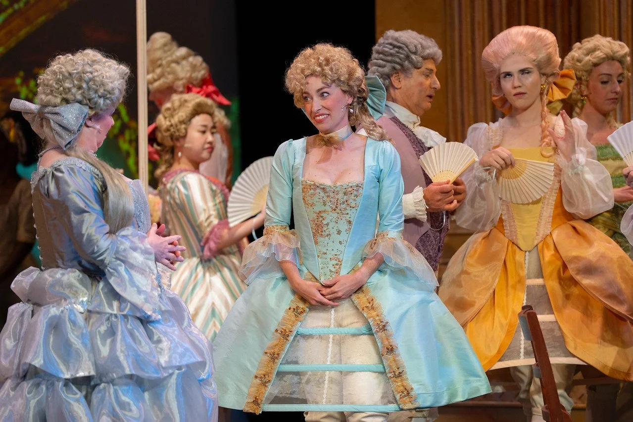  Leslie as Lady Lilette Sauvoirfaire, wearing a blue dress and blond wig, in  By Georges!  with Lamplighters Music Theatre, pictured with castmates. Photo by Joe Giammarco. 