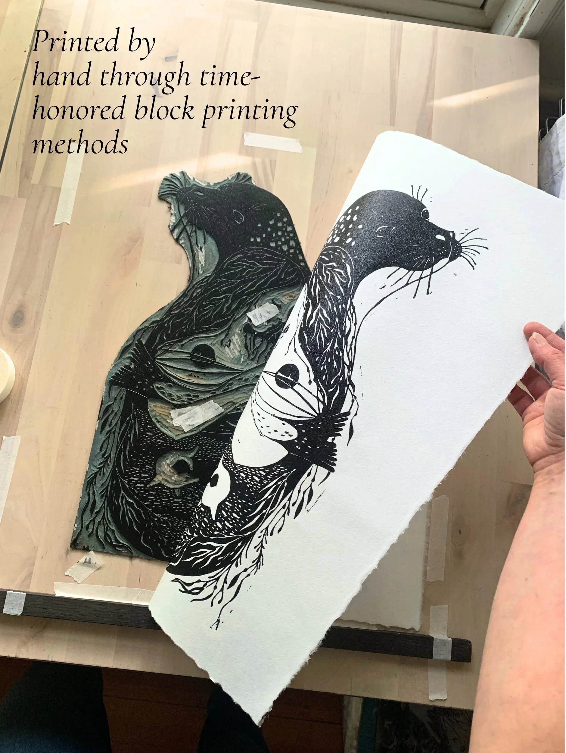 Artists hands hand printing a Selkie linocut
