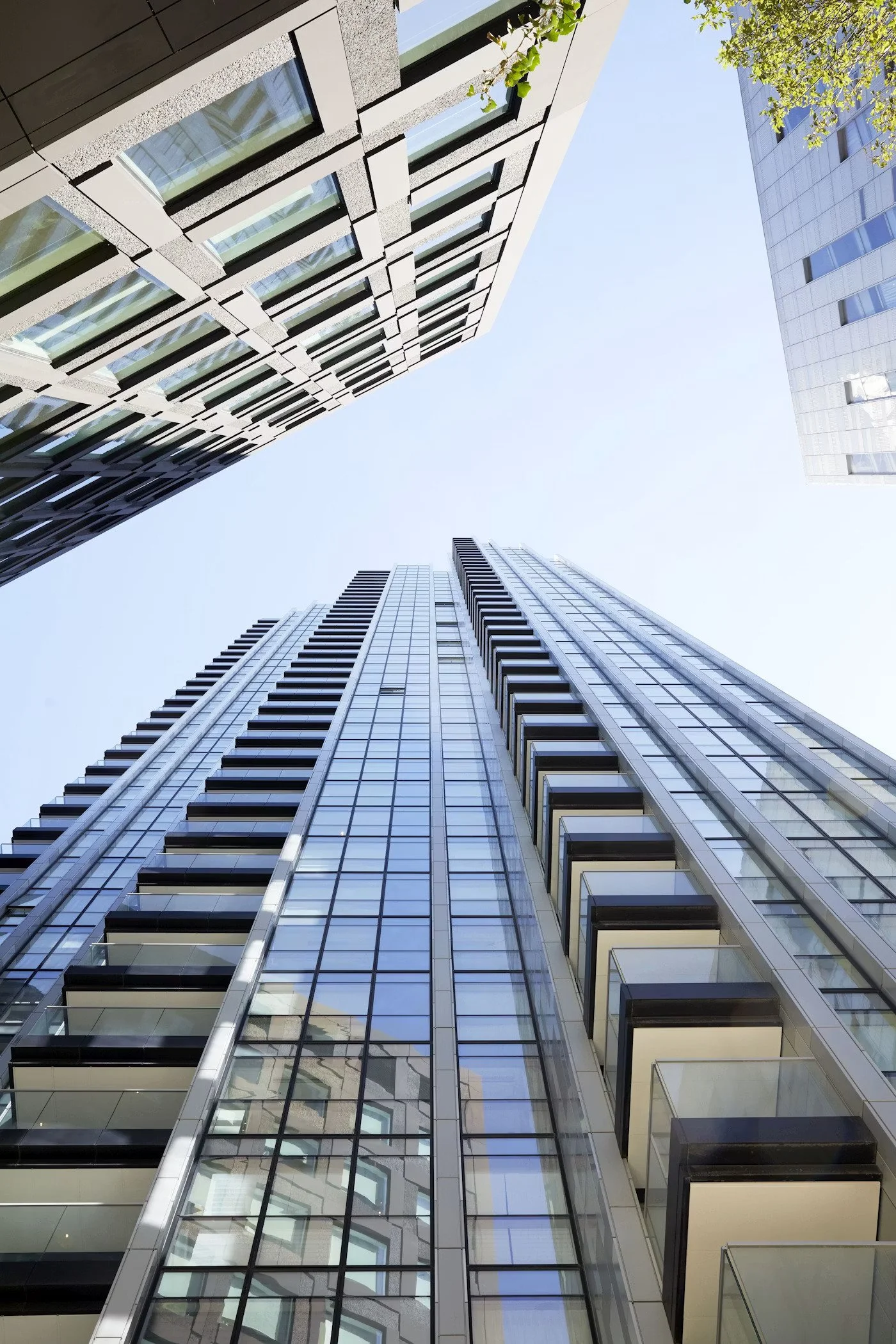 Looking up at modern glass and steel skyscrapers with reflective windows in an urban cityscape.