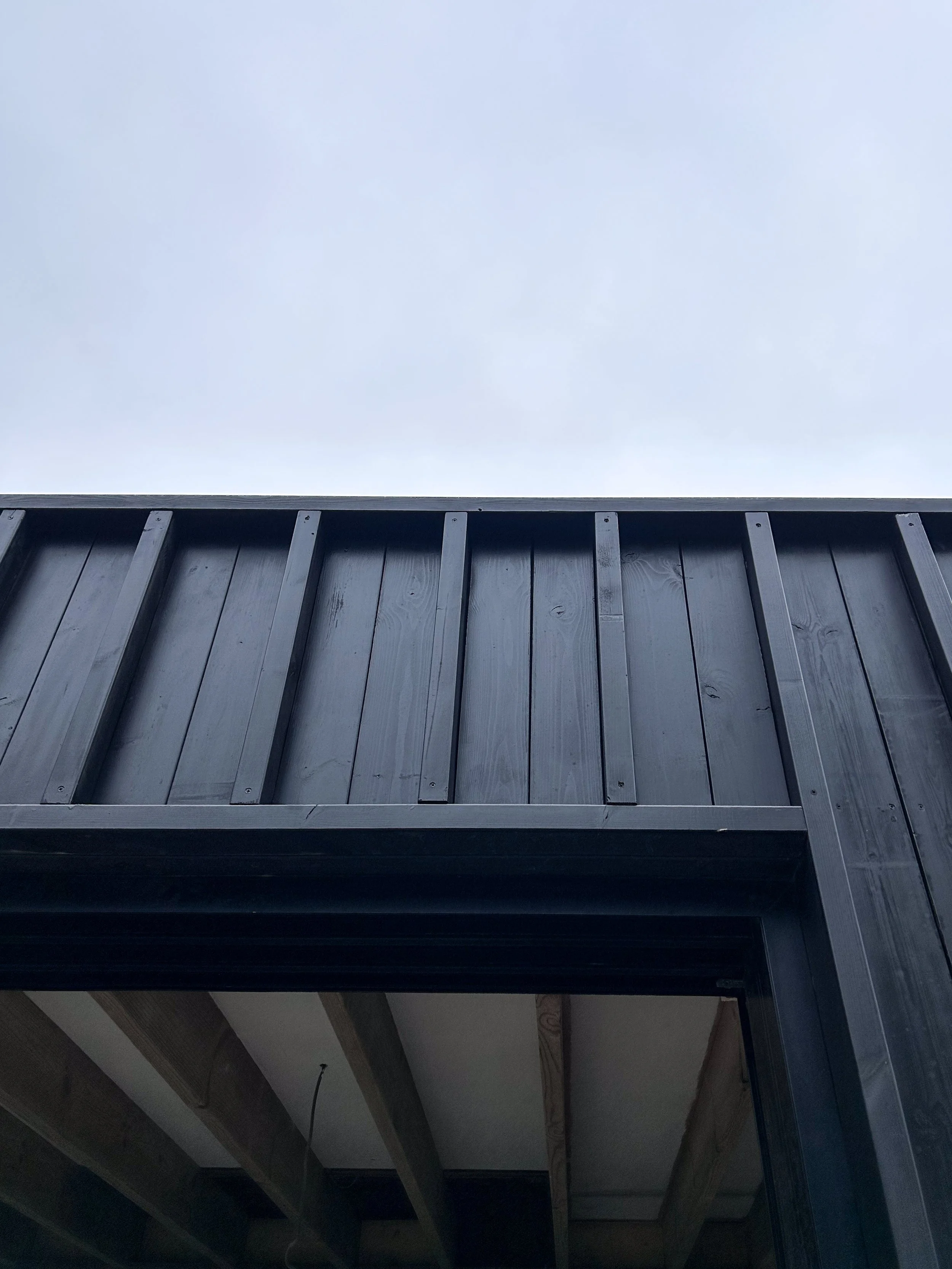 A black wooden fence against a cloudy sky, viewed from below.