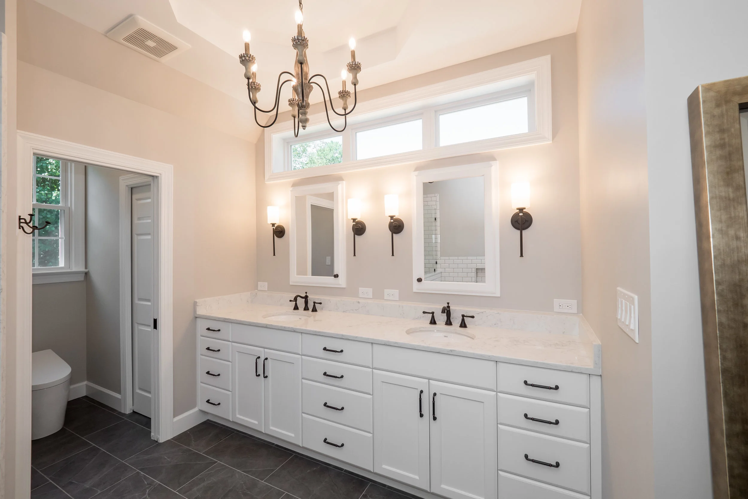 Elegant bathroom renovation with his and her sinks and chandelier