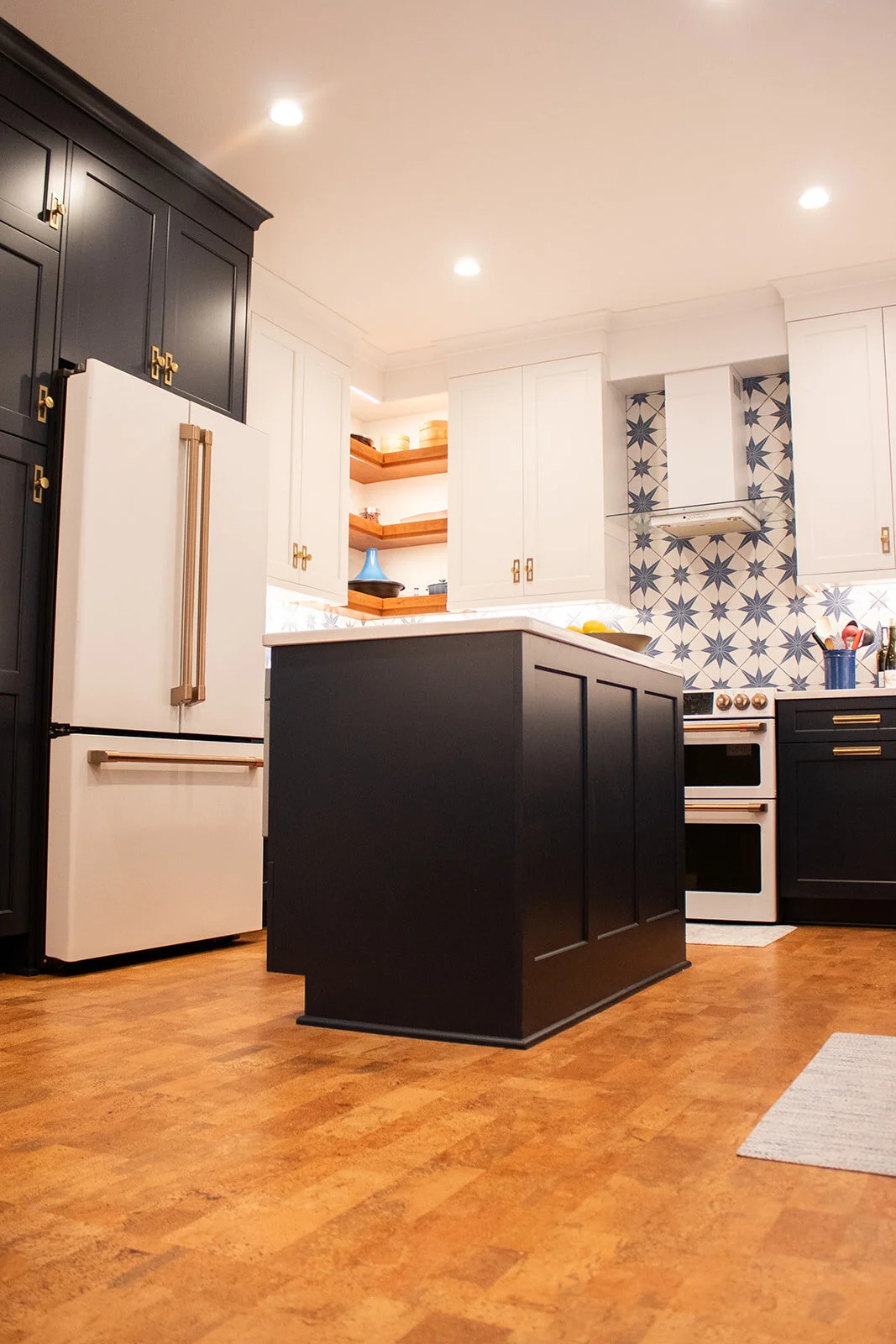 Kitchen with island, star tile backsplash, modern appliances, and cork floor