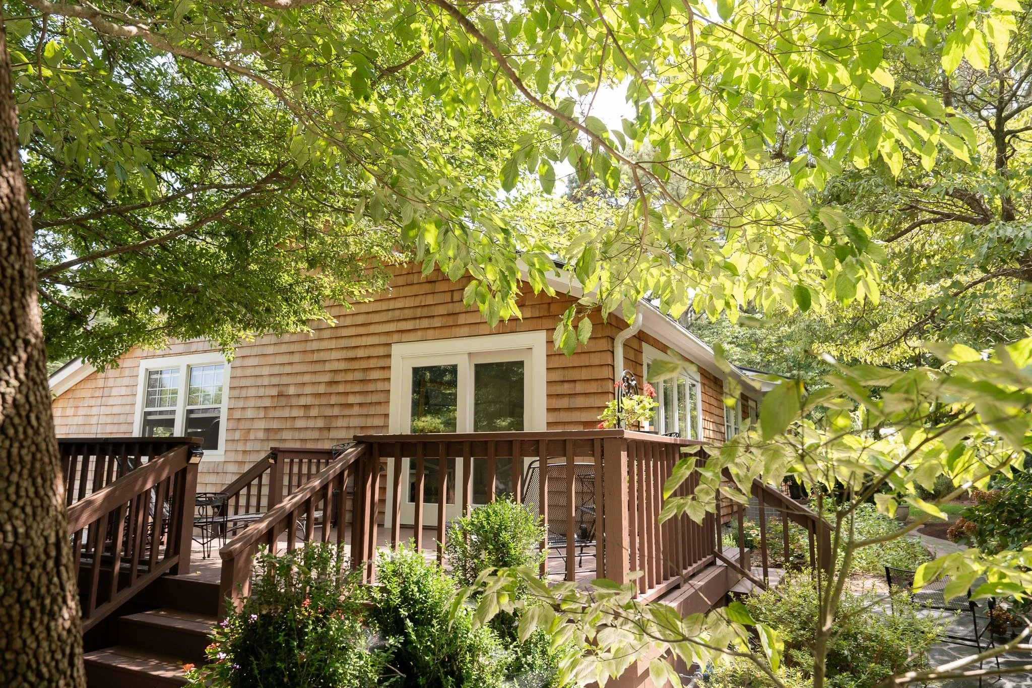 Side of home with western red cedar siding surrounded by green trees and light