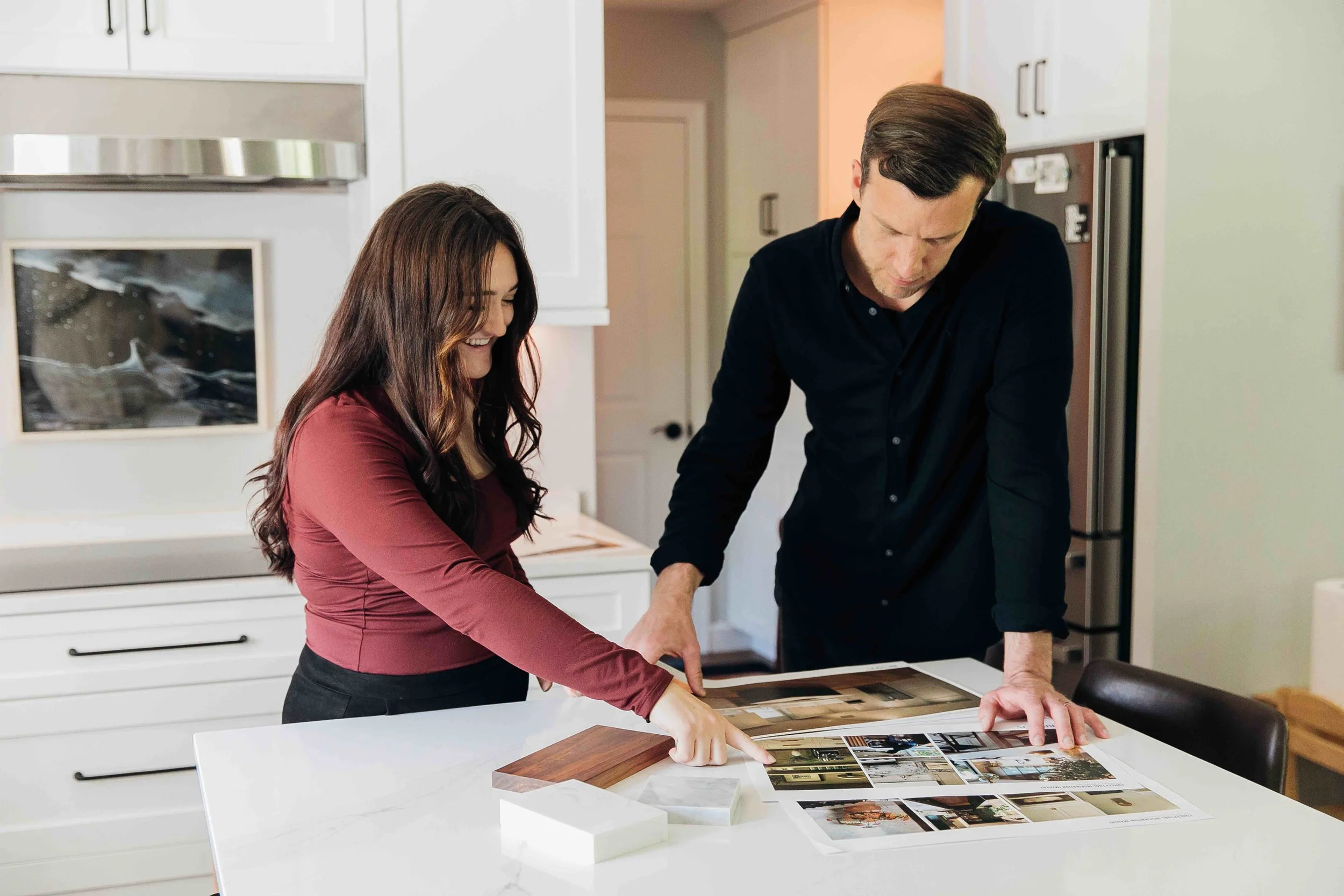 Woman and man looking at wood and tile selections and pointing at printed inspiration photos
