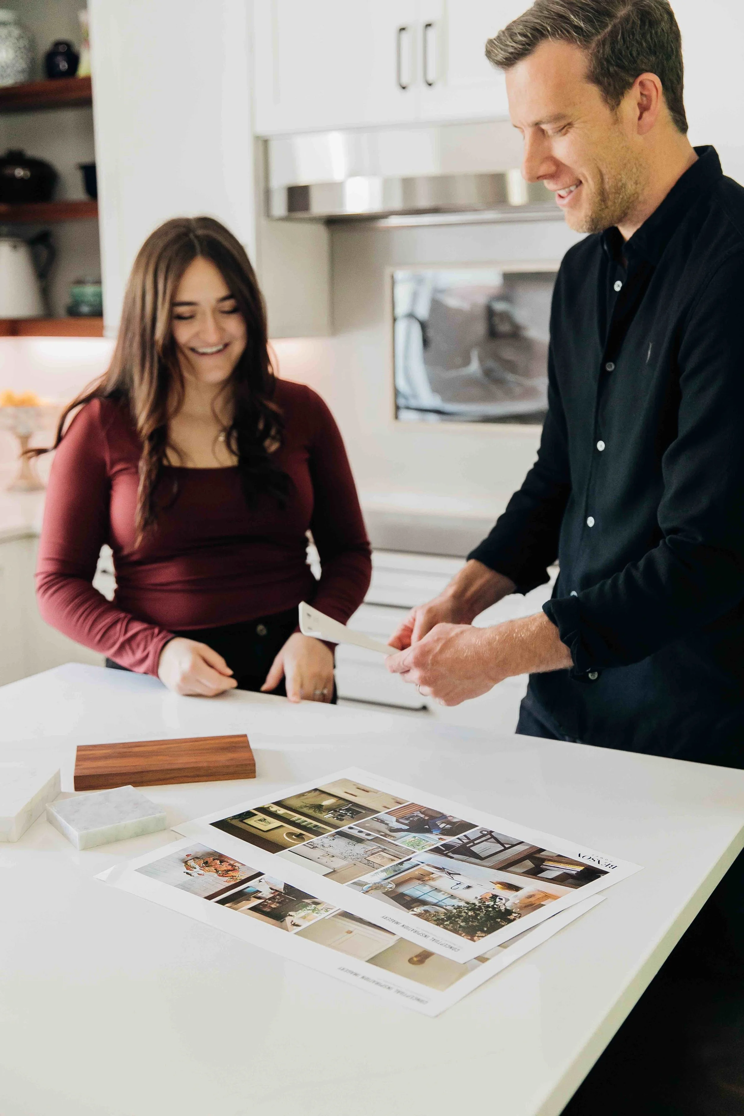 Man and woman looking at selections, paint samples, and inspiration imagery in a kitchen