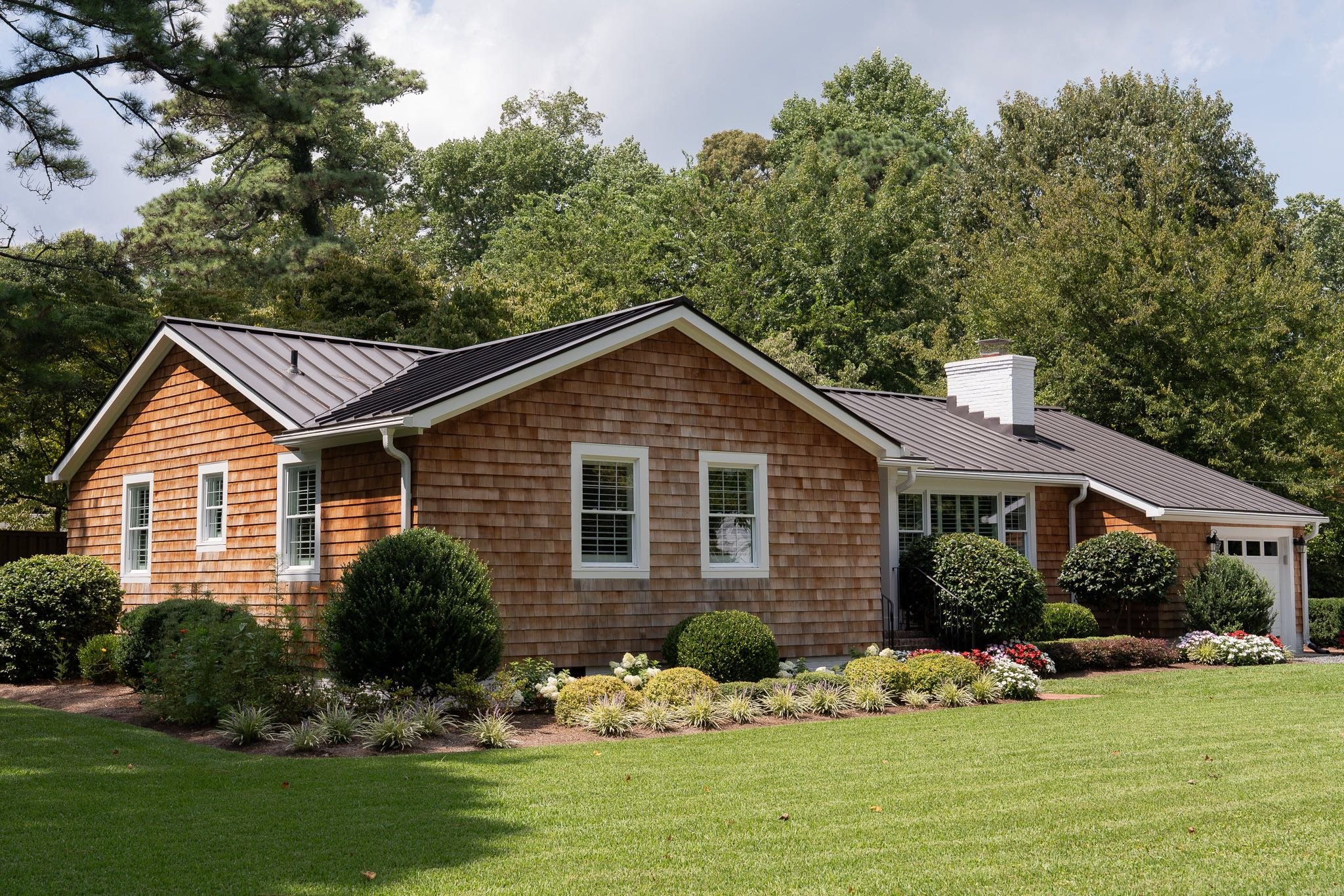 Angled view of ranch home with western red cedar siding and black metal roof