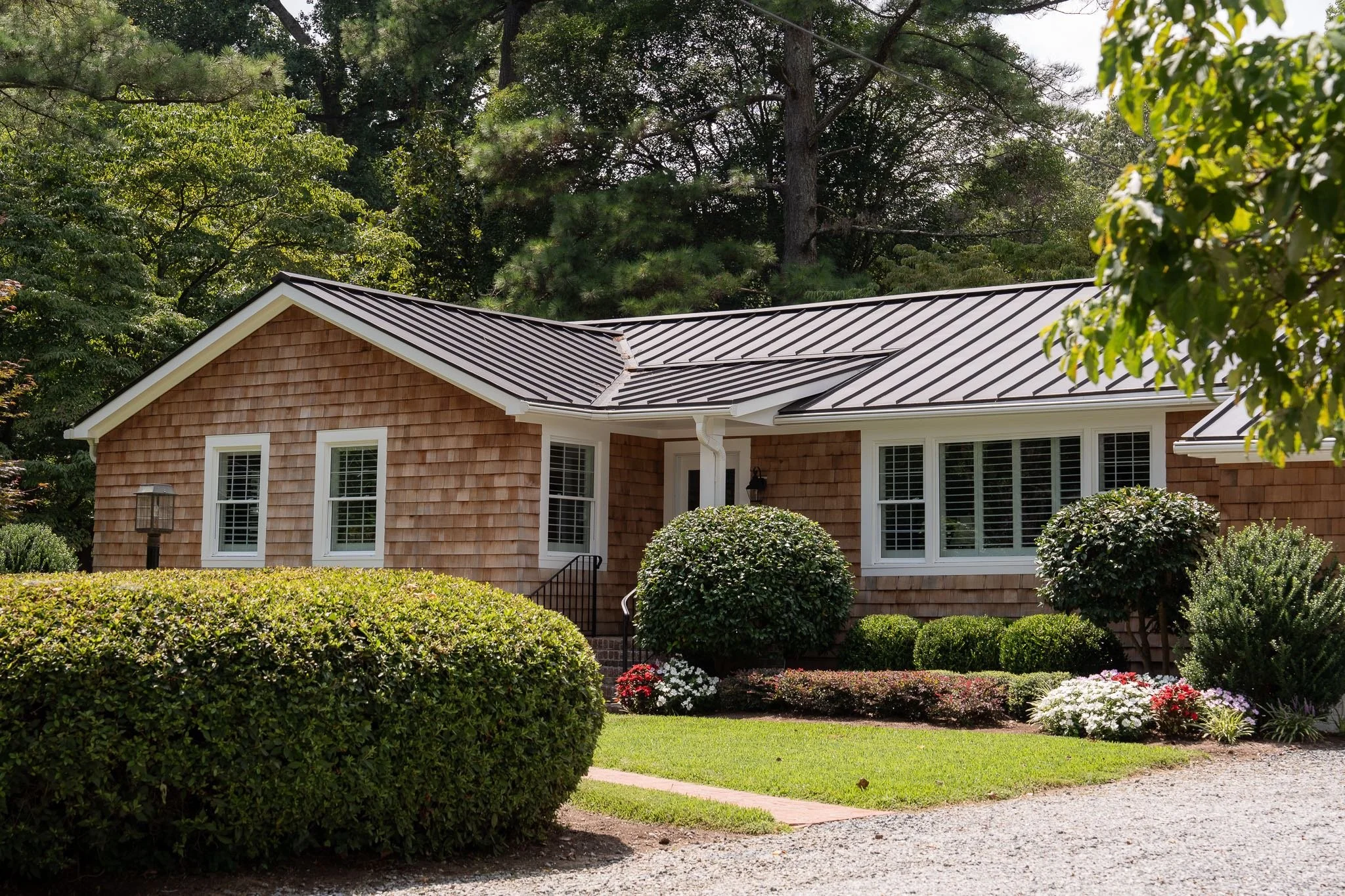 Bay Colony ranch home with cedar siding and black metal roof