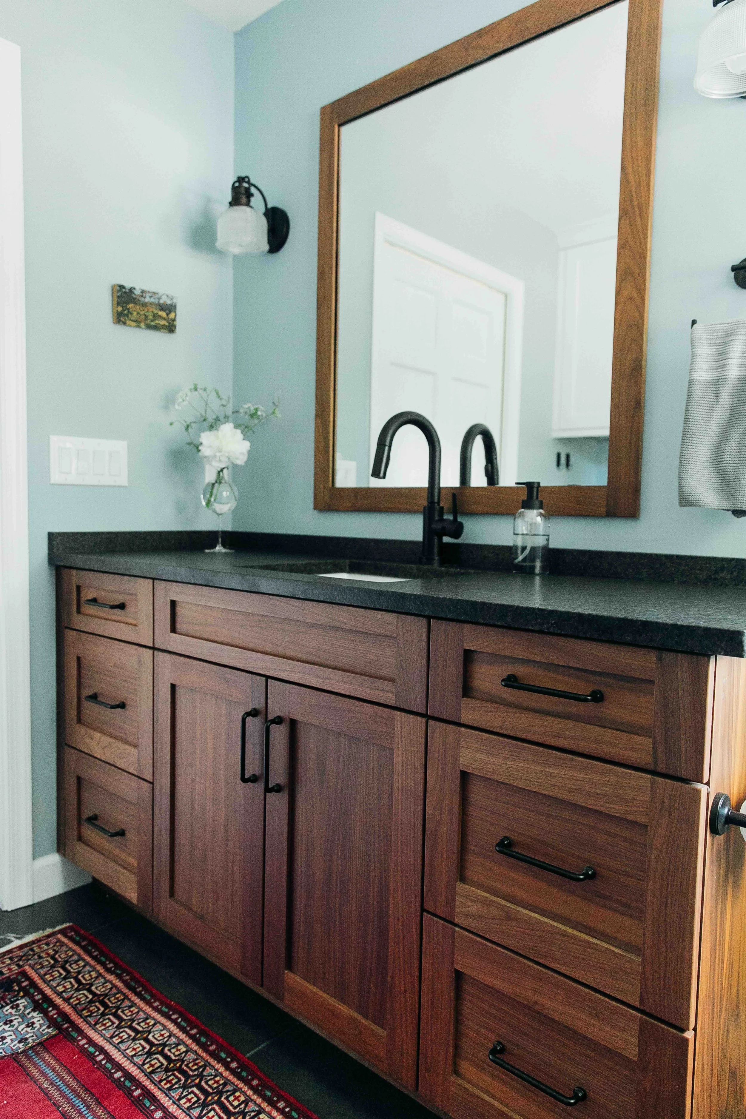 Guest bathroom in 1960s home with slate grey, black fixtures, and walnut wood cabinets