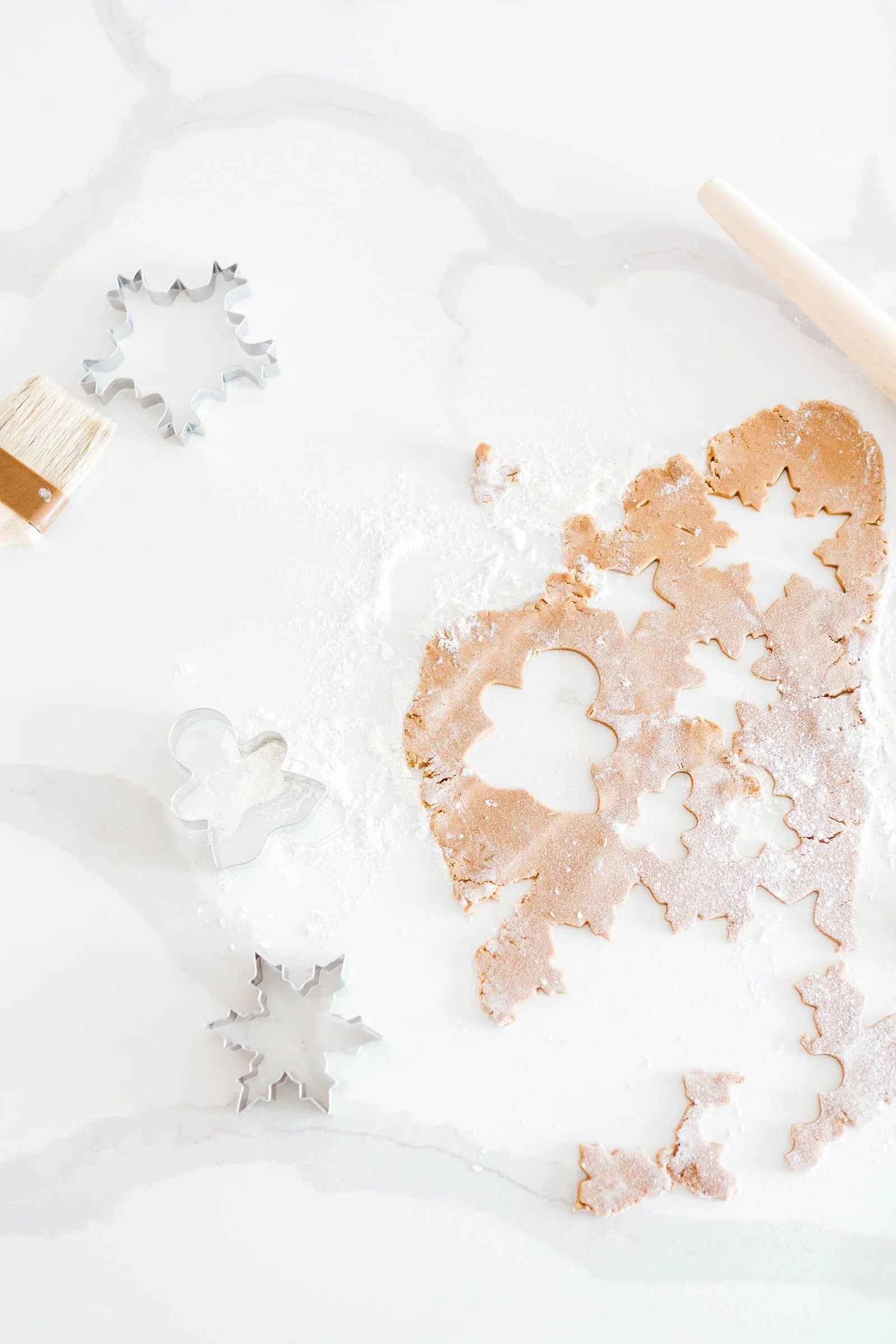Rolled out christmas cookies on white counter with snowflake and gingerbread man cookie cutters