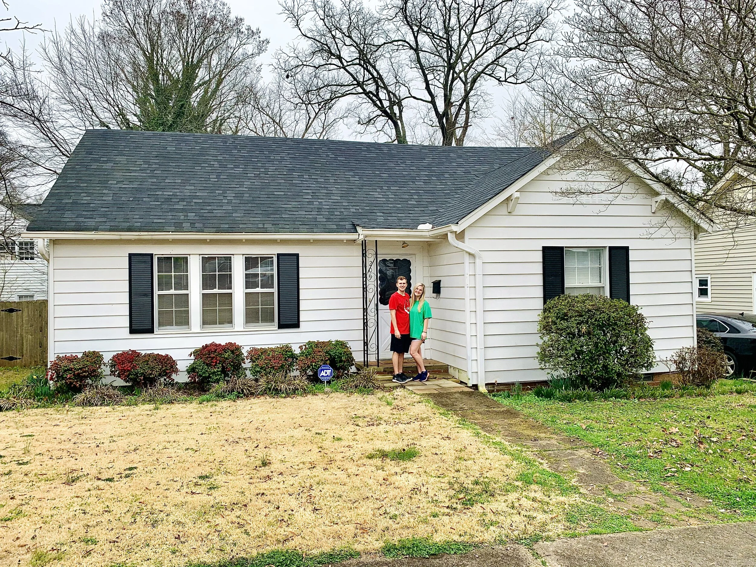 Erica and her husband, Jackson, smiling in front of their previous home in Carrollton.