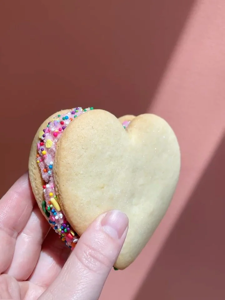 Happy Pride ya&rsquo;ll! We love all of you and made these Raspberry Heart Sandwich Cookies to show you just that. 
Lemon sugar cookie filled with a raspberry buttercream and a surprise raspberry jam. Coated in cutie sprinkles and some sparkly glitte