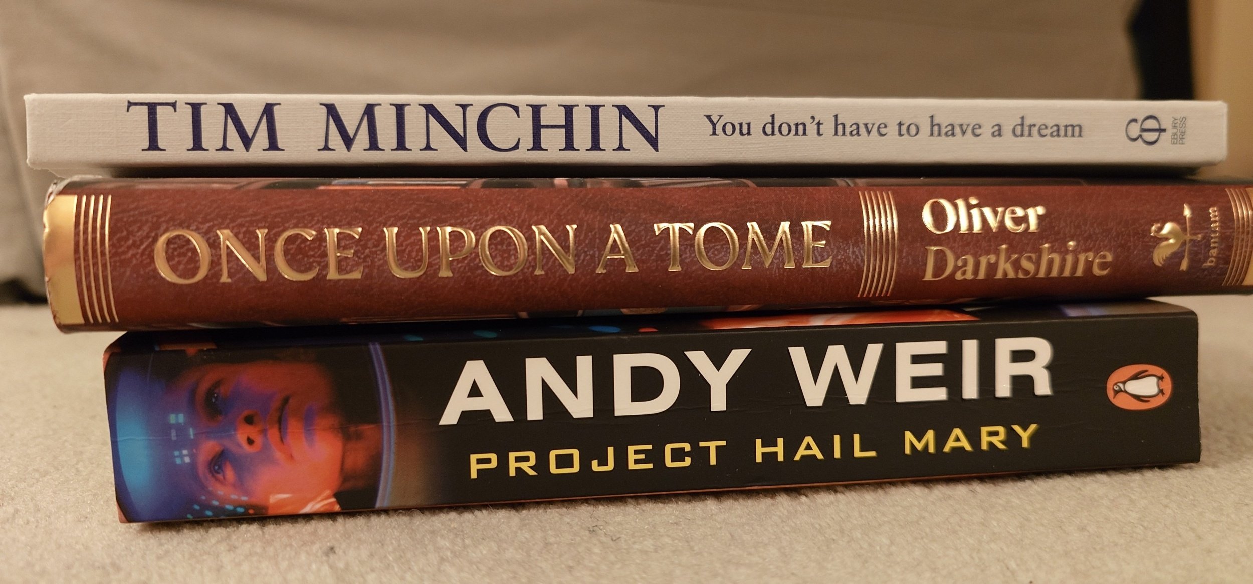 A small pile of all the books mentioned in the post, piled up on a grey carpet.