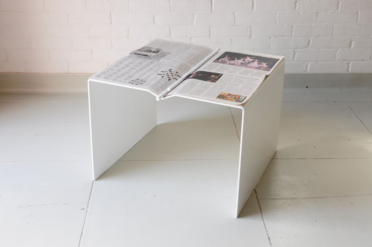   Newspaper Table by Isaac Yu Chen  This design looks at the coffee table and interactions that take place around it. By creating a dimple in the surface and using a weighted rod, the act of reading the newspaper and also using it as a table cloth ar