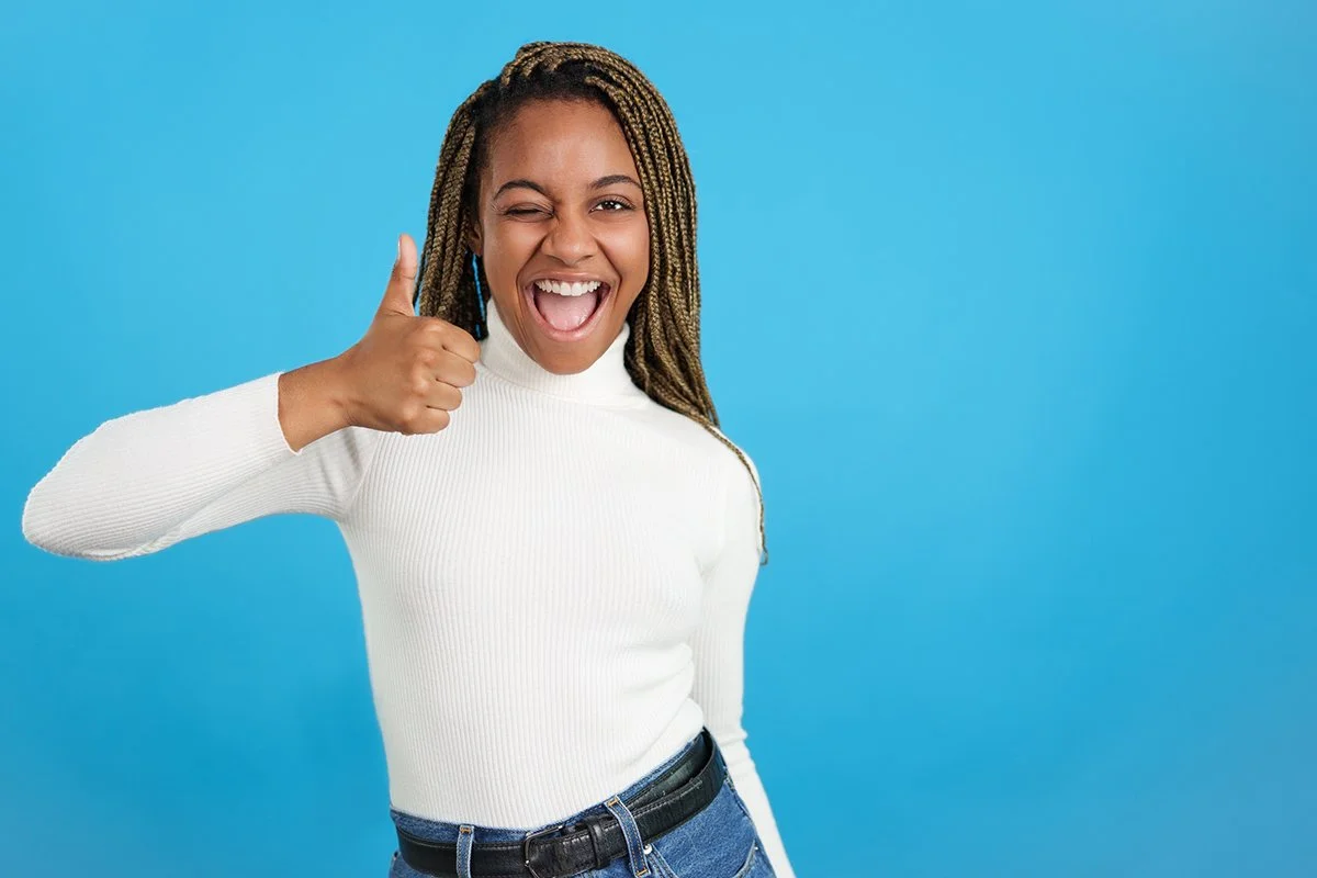 Happy young woman winking and giving a thumbs up.