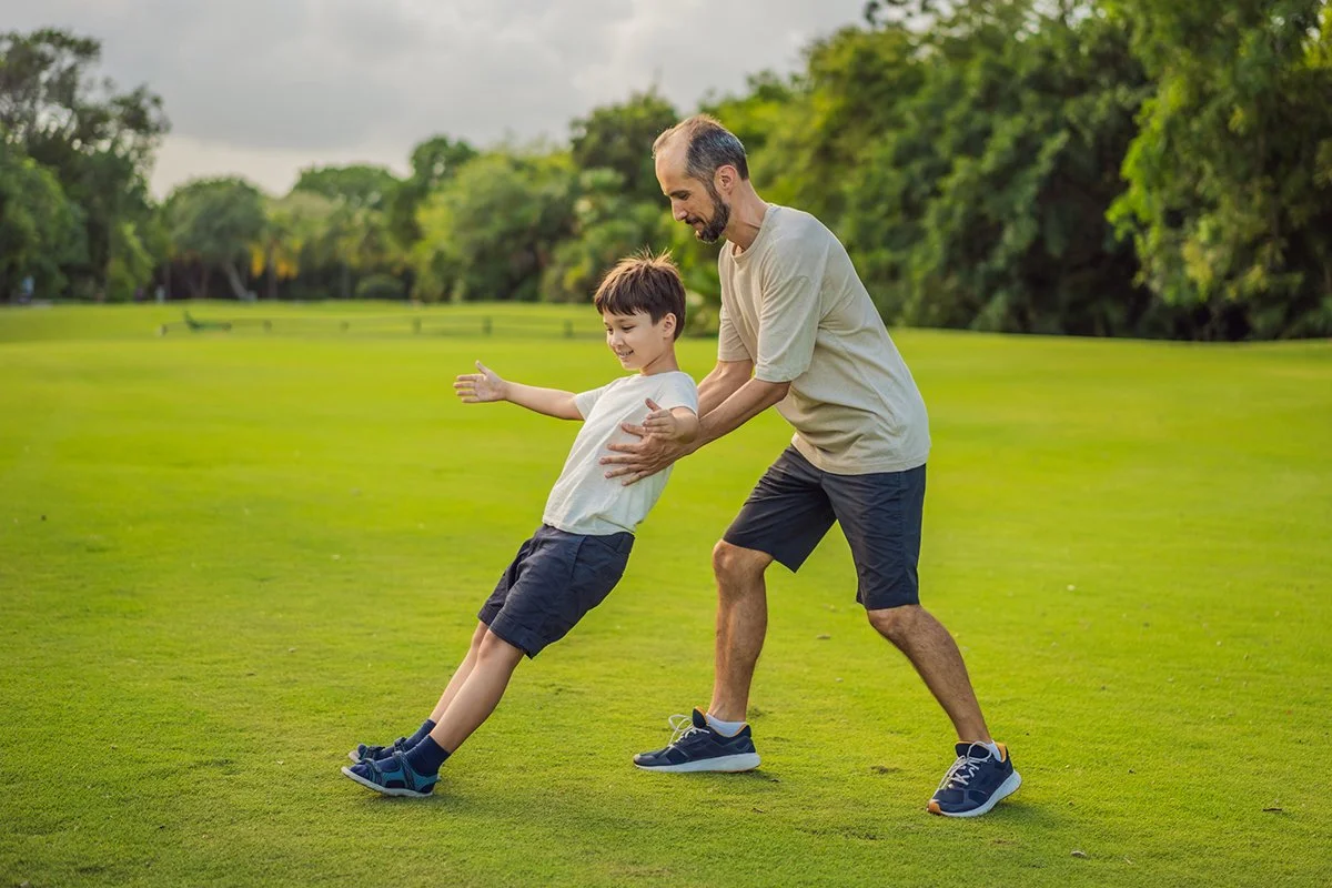 A touching trust exercise as a son falls back into his father's arms, demonstrating unwavering trust and the bond between parent and child.