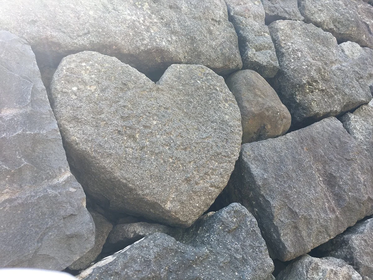 Close up of a heart shaped stone built into a rock wall.