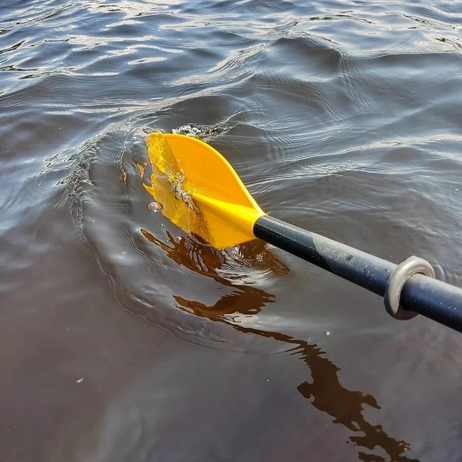 A close up of a yellow paddle , paddling in the river.