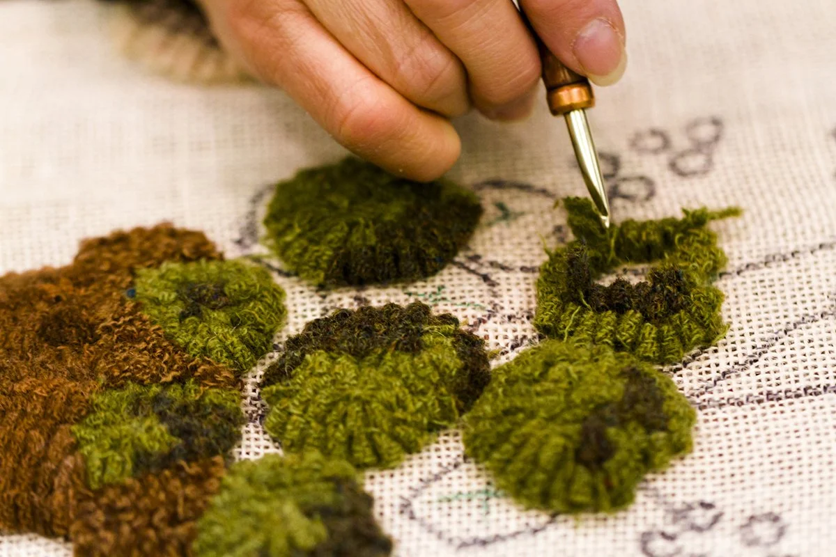 Close up image of a hand and hook doing Rug Hooking