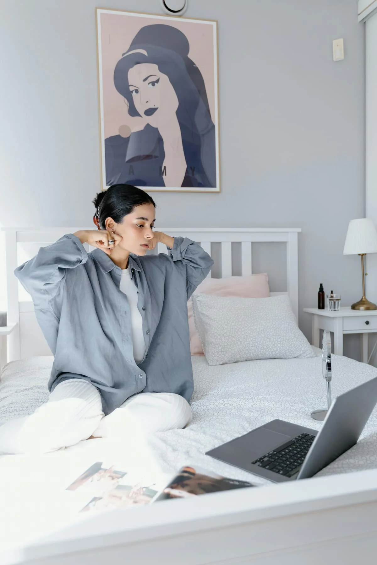 woman in bed with laptop does an online yoga therapy session for somatic healing