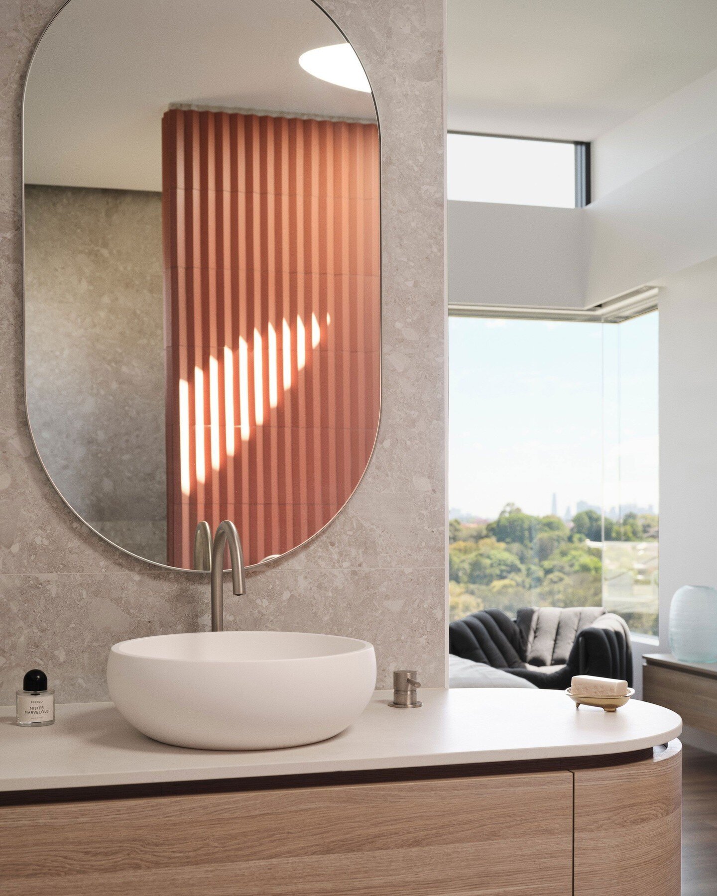 The brief was to create a main ensuite that included the city view. We designed his and hers vanities on each side of the ensuite entry so the views across the main bedroom are captured. The timber joinery on each side is curved for softness.  Placem