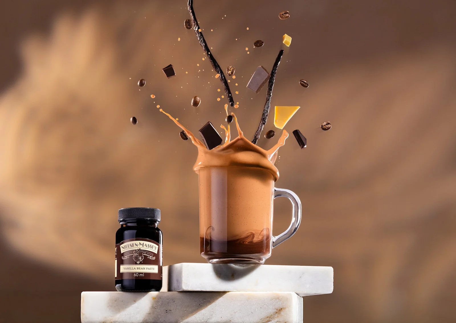 Coffee beans, chocolate chunks and vanilla pods flying out of a mocha photographed by Matt Madden Visuals and styled by Mandy Thompson and Tamsin Weston.jpg