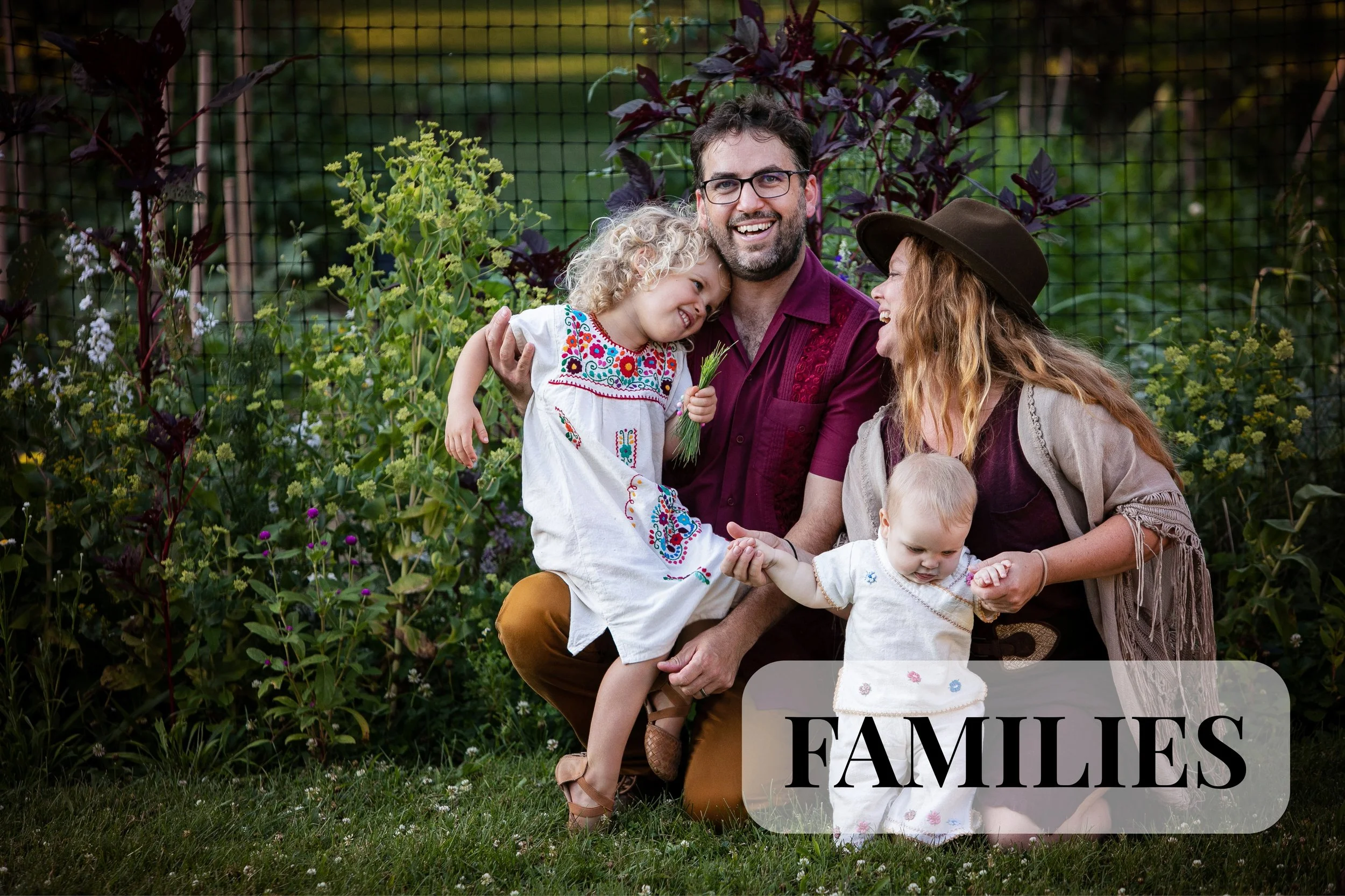 A family photo session in Camp Dennison, Ohio. A happy family of four, including a man, woman, and two young children, enjoying time together outdoors amidst lush plants and flowers, with a netted background. The woman is wearing a brown hat, and the