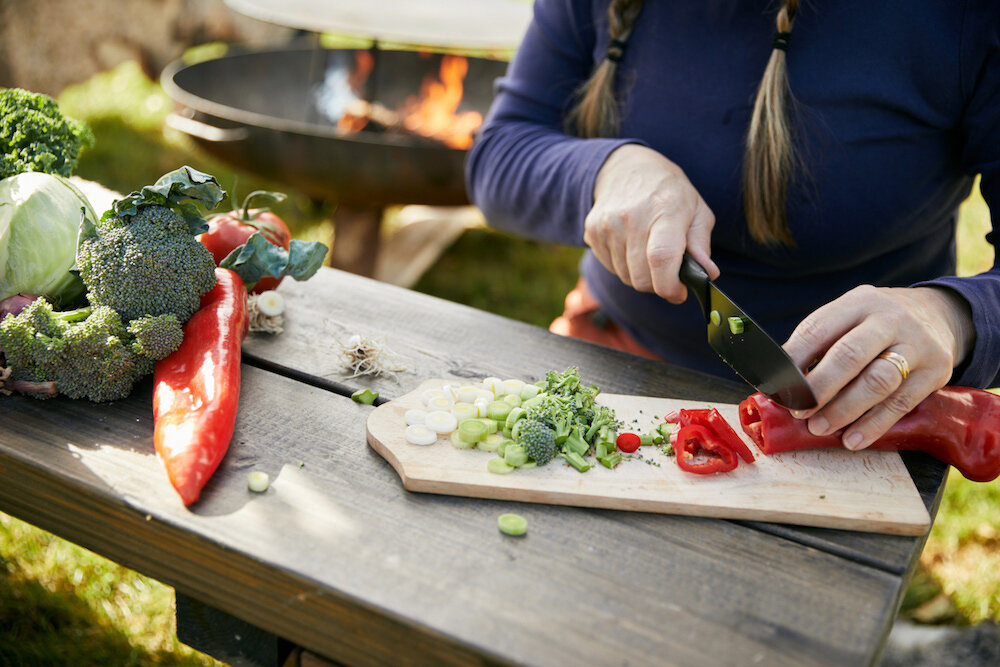 kvinna hackar lokala grönsaker från bergums skafferi utomhus på en skärbräda vid aktiv matlagning hos pevon ecoturism