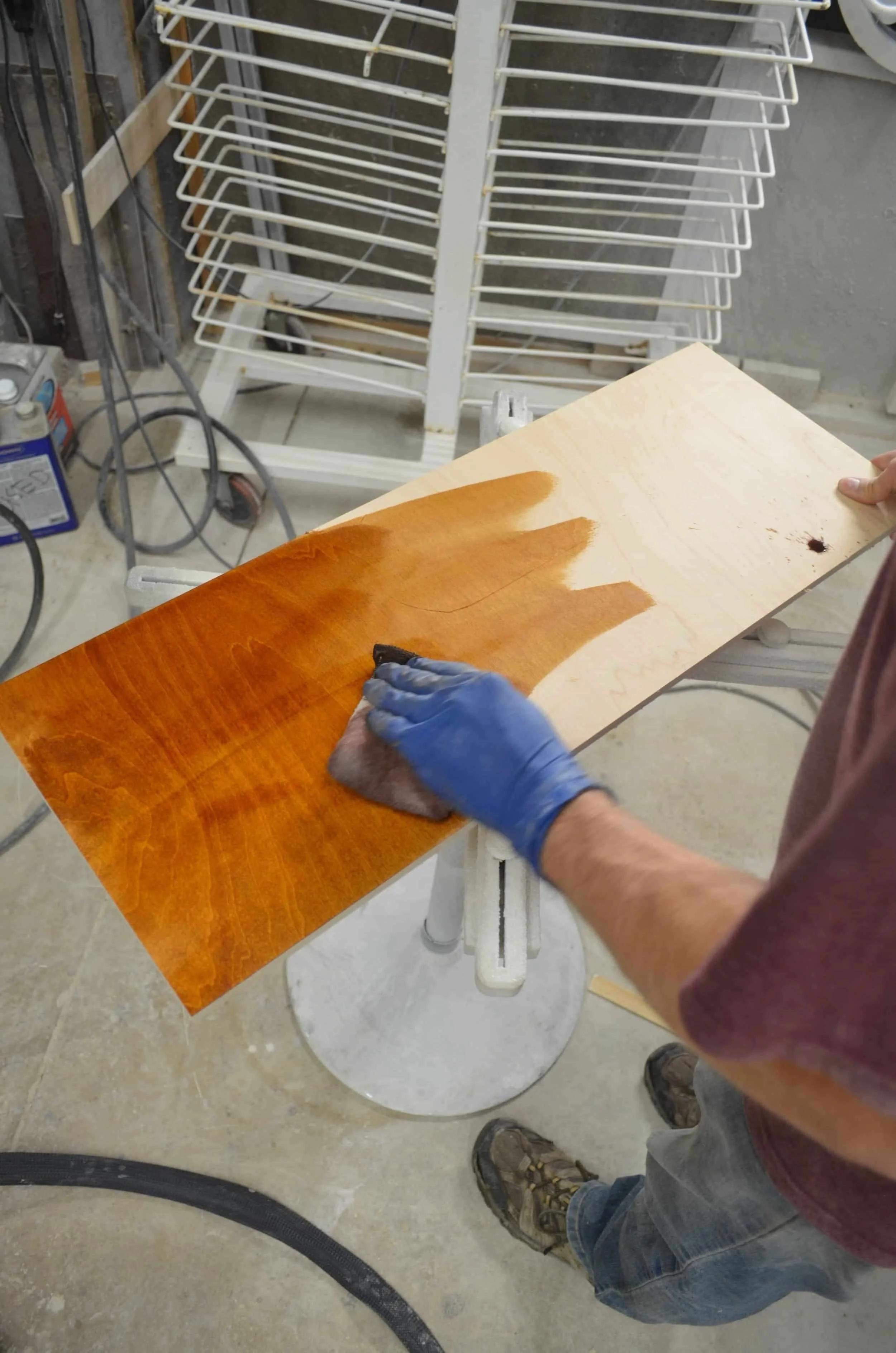 Craftsman hand-applying custom wood stain to solid hardwood cabinet using traditional finishing techniques