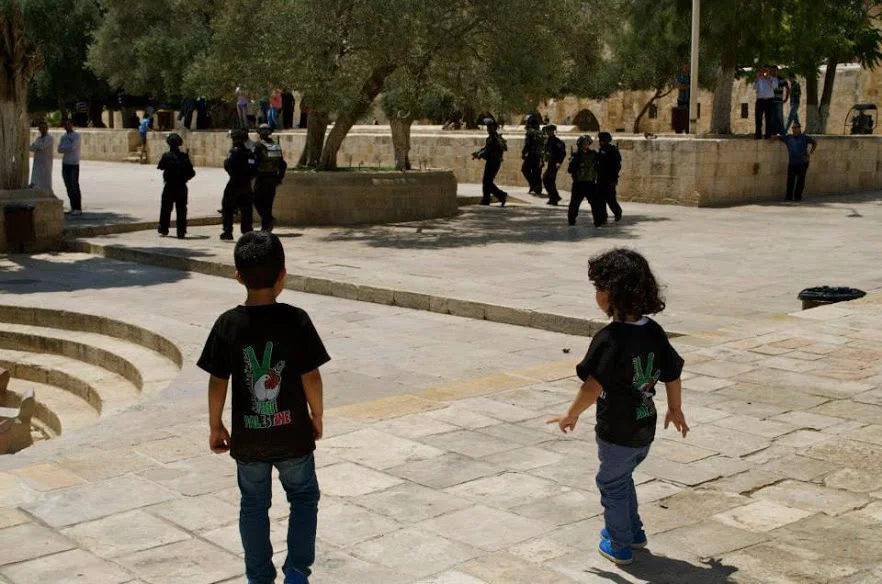Two young Palestinian boys follow Israeli Defense Force soldiers at Al-Aqsa compound during an IDF raid in June 2014. | Rasha Abousalem