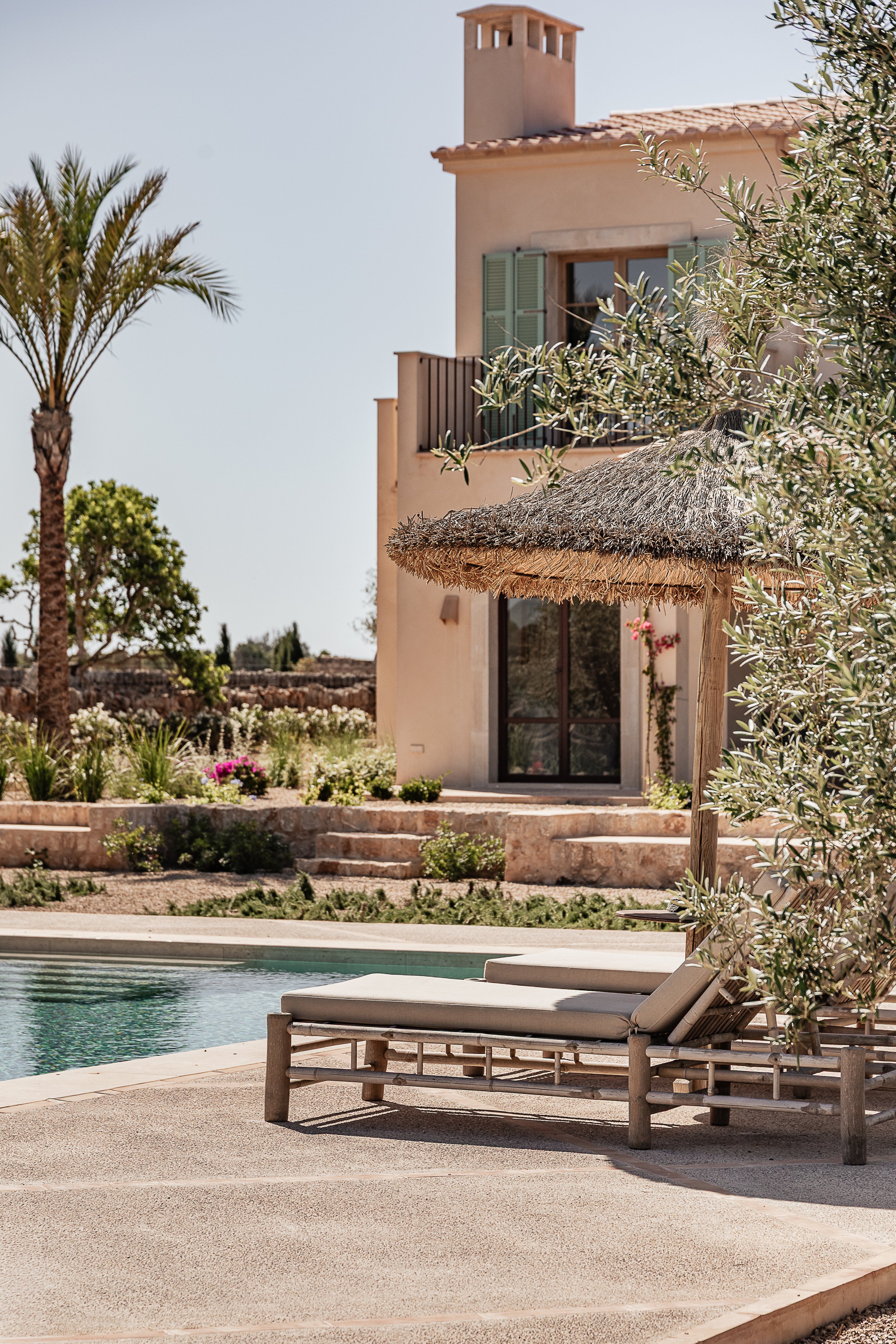 Exterior of a Mediterranean family home in Mallorca featuring lime-rendered walls, natural stone, green shutters and native landscaping by espanyolet.