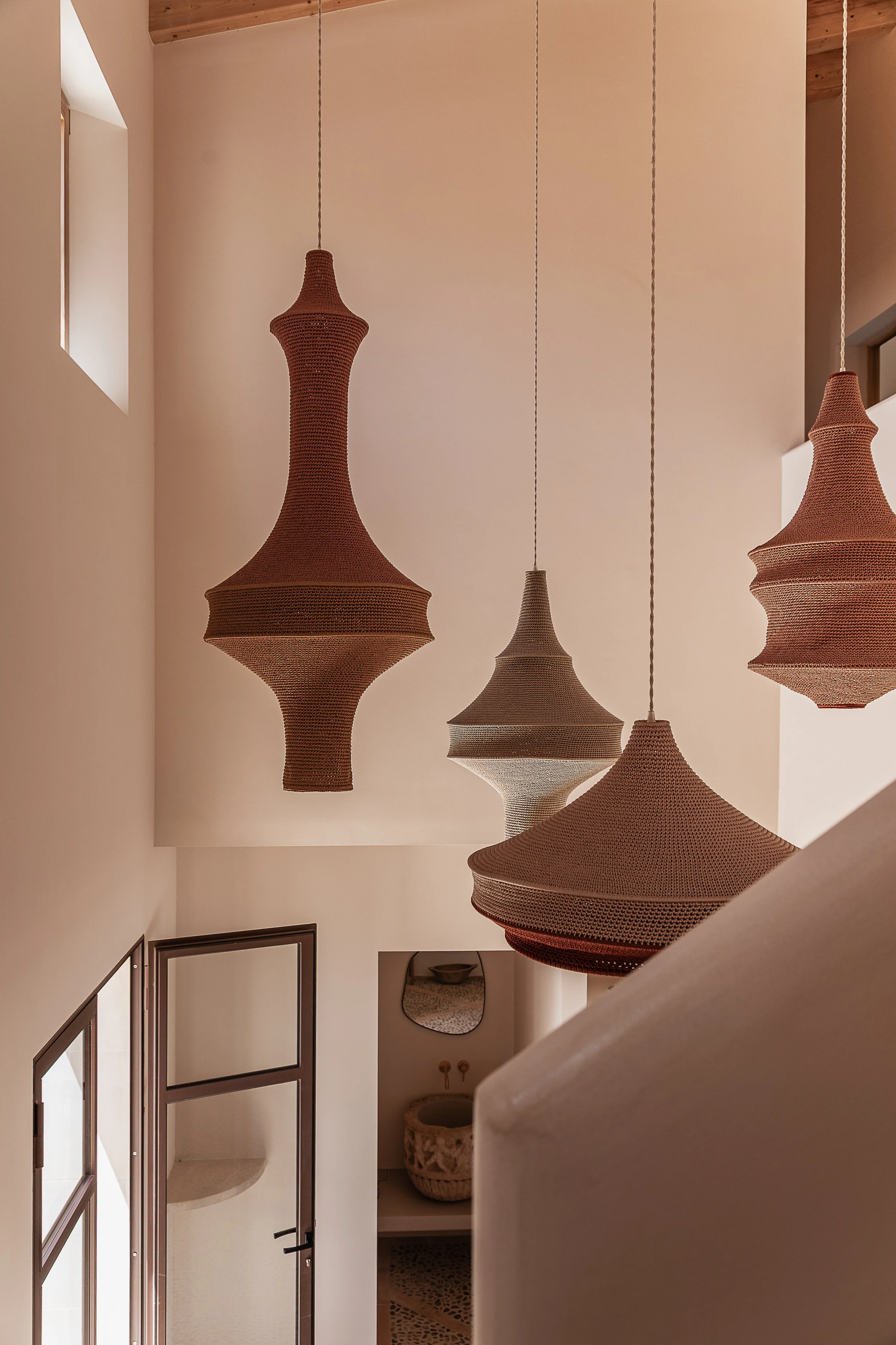 Handwoven Hamimi pendant lights suspended above the entrance hall, creating a sculptural focal point in a Mediterranean home in Mallorca.