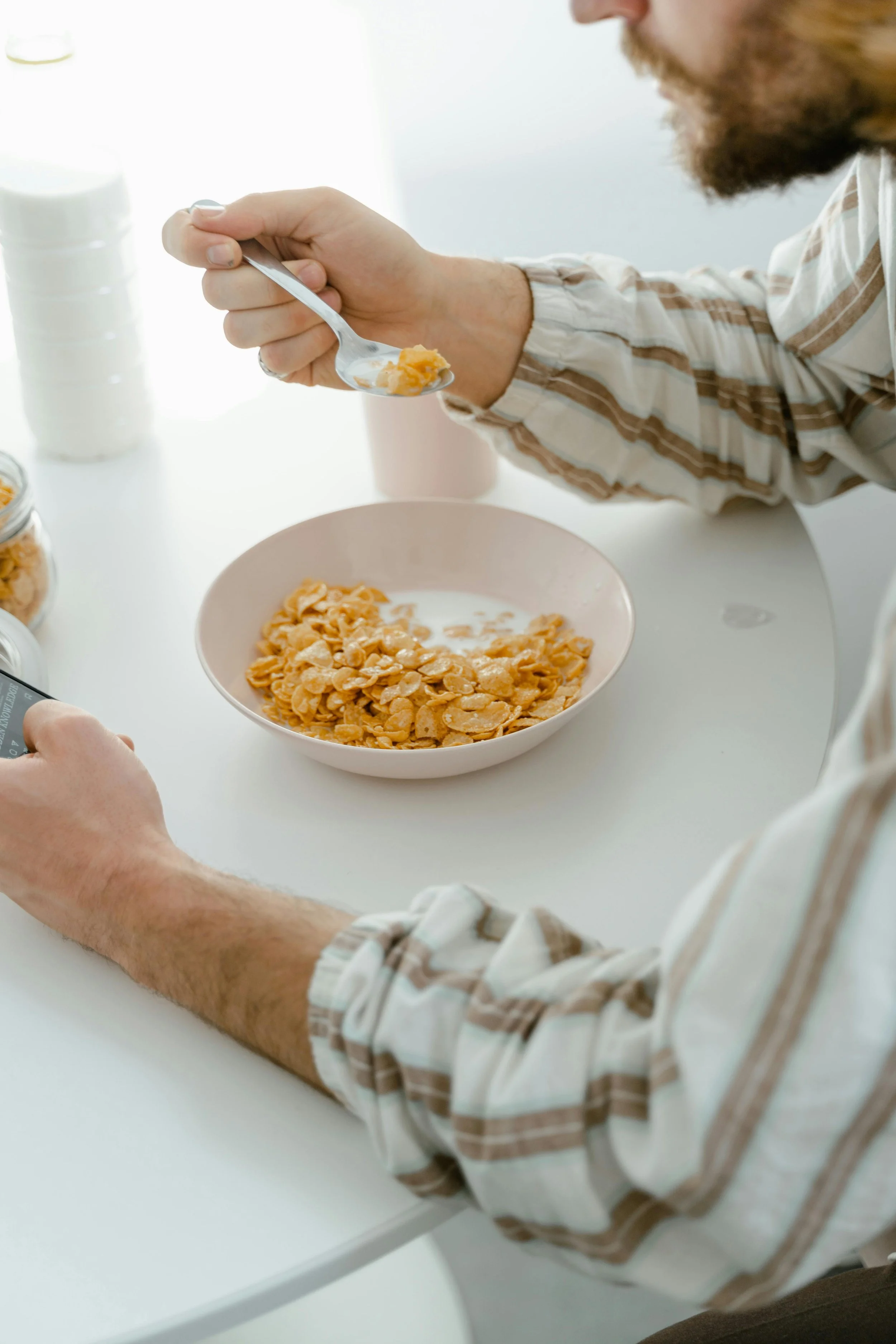 Man eating cornflakes while scrolling on a phone