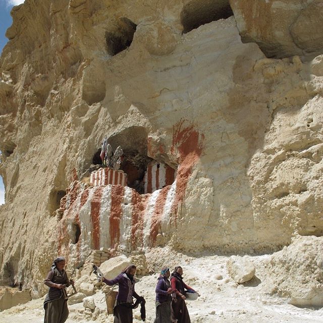 April/2012 _ Northern Mustang District, Nepal 
Troglodyte caves carved into ocher cliffs. The red and white, primitive paintings on the large mouth of the cave form an impressive backdrop behind the women who accomplish together with smile, elegance 