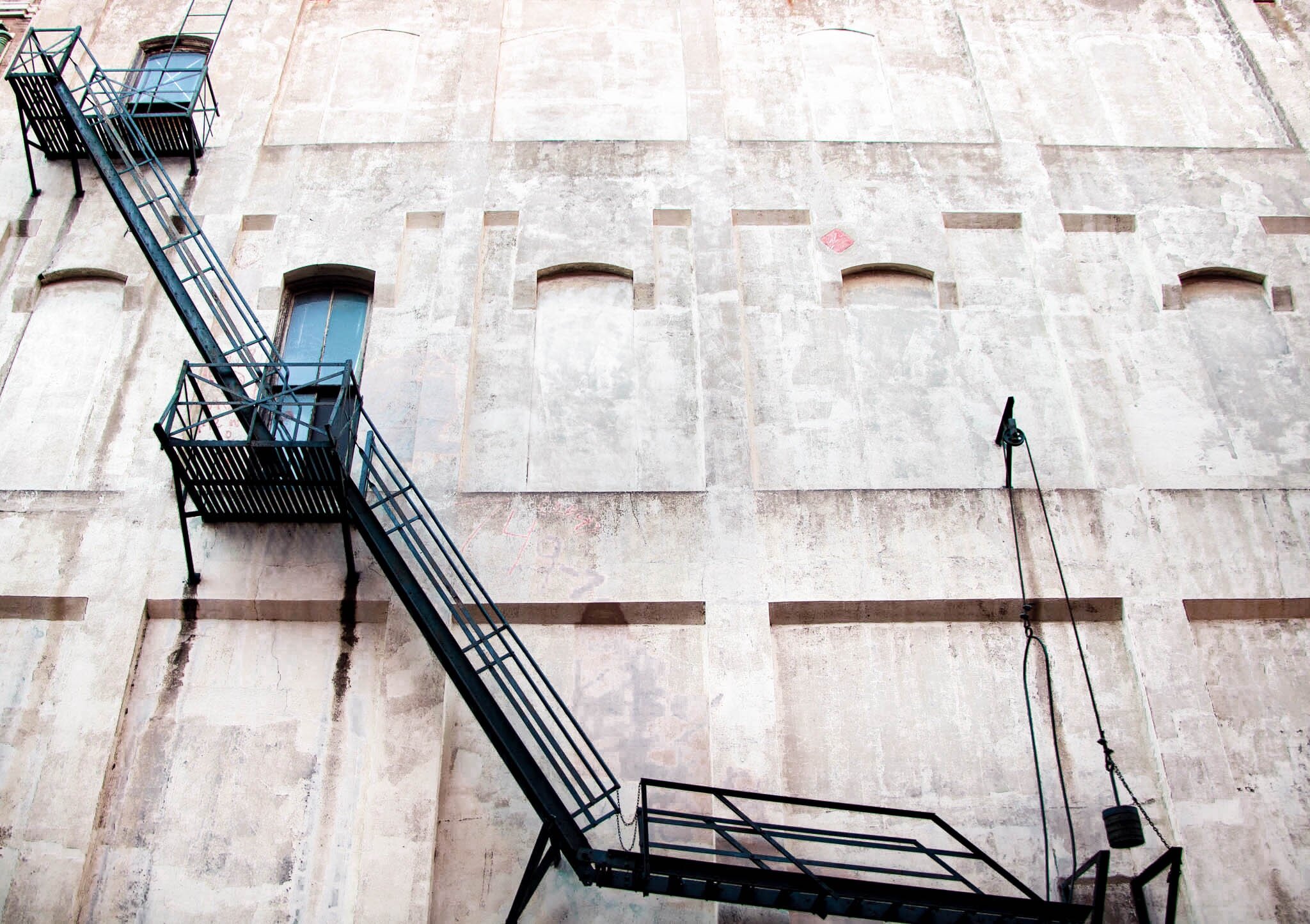 Exterior of an old building with a diagonal fire escape staircase and weathered wall
