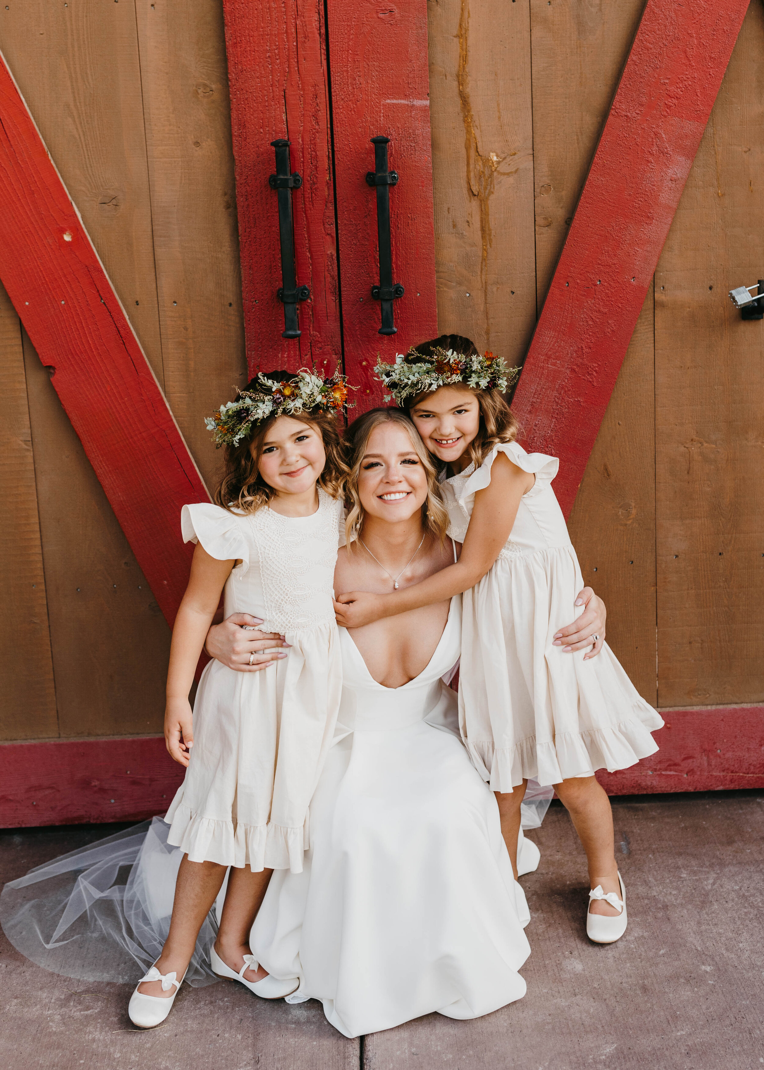  This Cache Valley, Utah bride proudly poses with her two flower girls’s dressed in white and in custom Sweet Afton Floral flower crowns. wedding flower crown, flower girl flower crown, custom wedding florals in cache valley utah, professional weddin