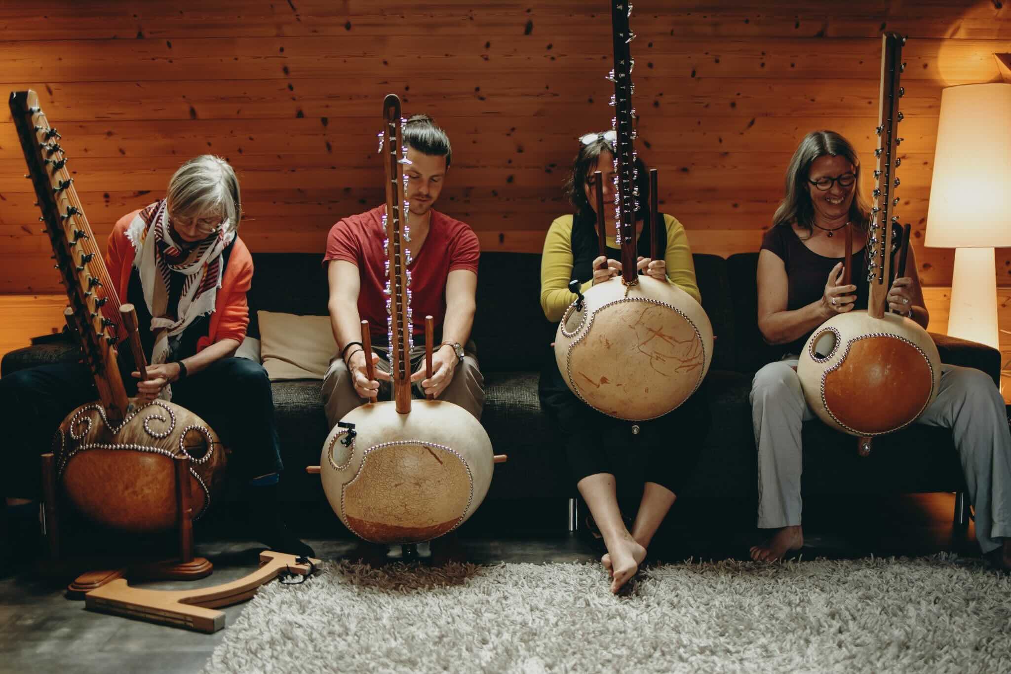 Josh Doughty teaching at a kora workshop, surrounded by students playing traditional West African koras in a warm wooden room. The session focuses on rhythm, technique, and the jali (griot) tradition.