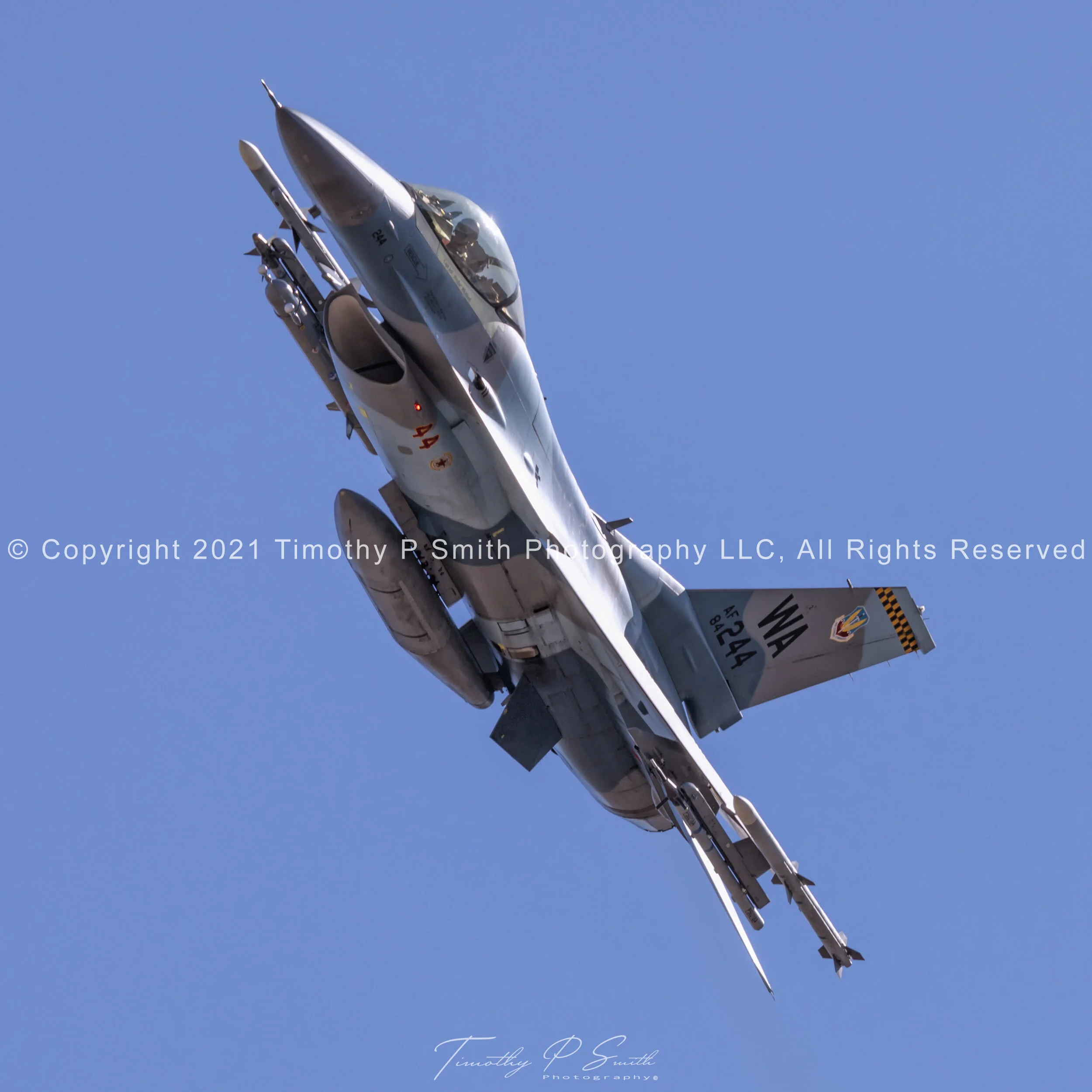 F-16C “Blue Flanker” of the 64th Aggressor Squadron in flex departure from Nellis AFB, showing topside camo, red star, and red intake numbers.