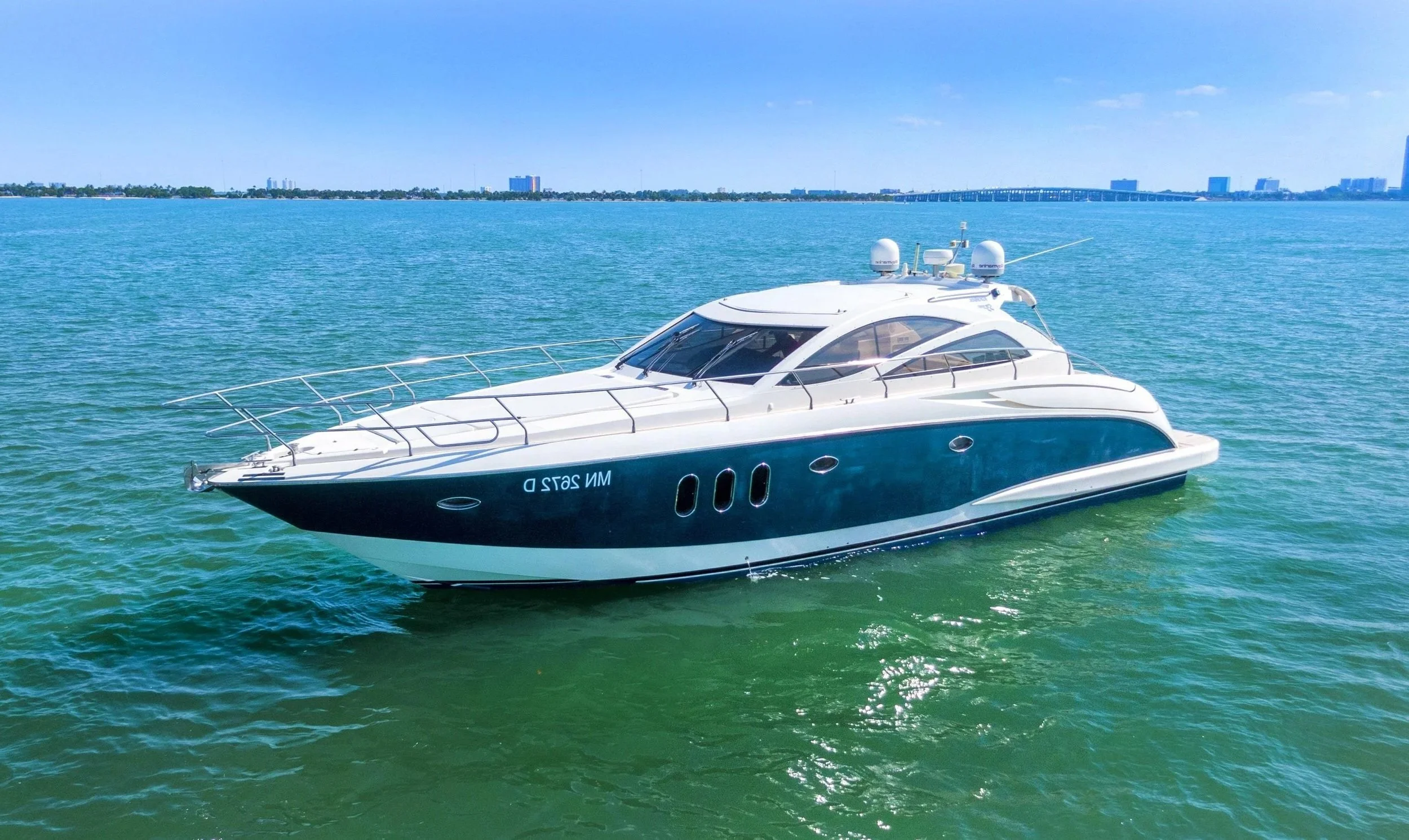Luxury motor yacht sailing on calm water with city skyline in the background