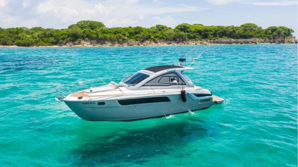 Luxury yacht floating on clear blue ocean waters near a green island.