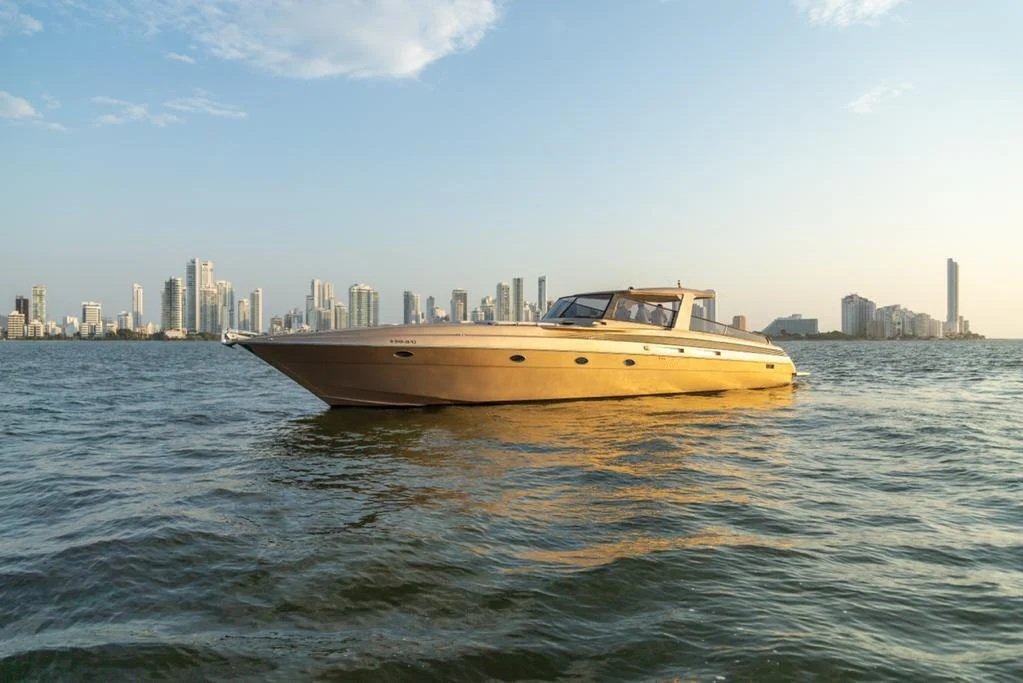 A luxury yacht floating on the water with a city skyline in the background during sunset or sunrise.