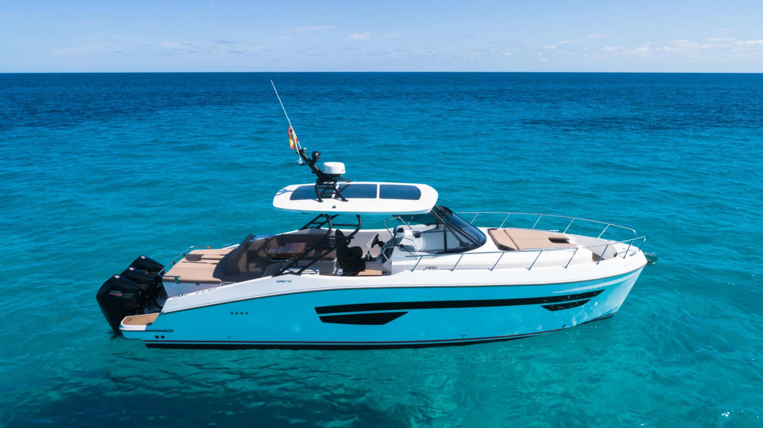 White motor yacht with black accents floating in clear blue ocean under partly cloudy sky.